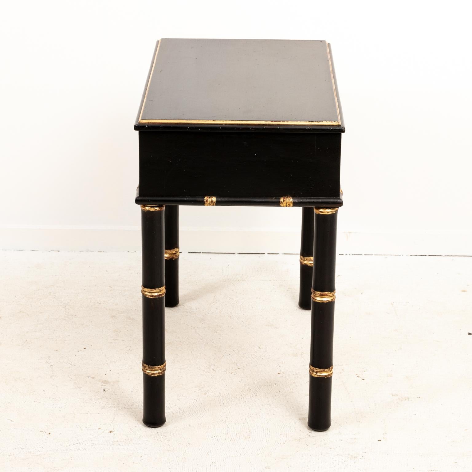 Black and gold Hollywood Regency style faux bamboo side table with one drawer on turned faux bamboo legs, circa 1970s. Made in the United States. Please note of wear consistent with age including minor paint loss.