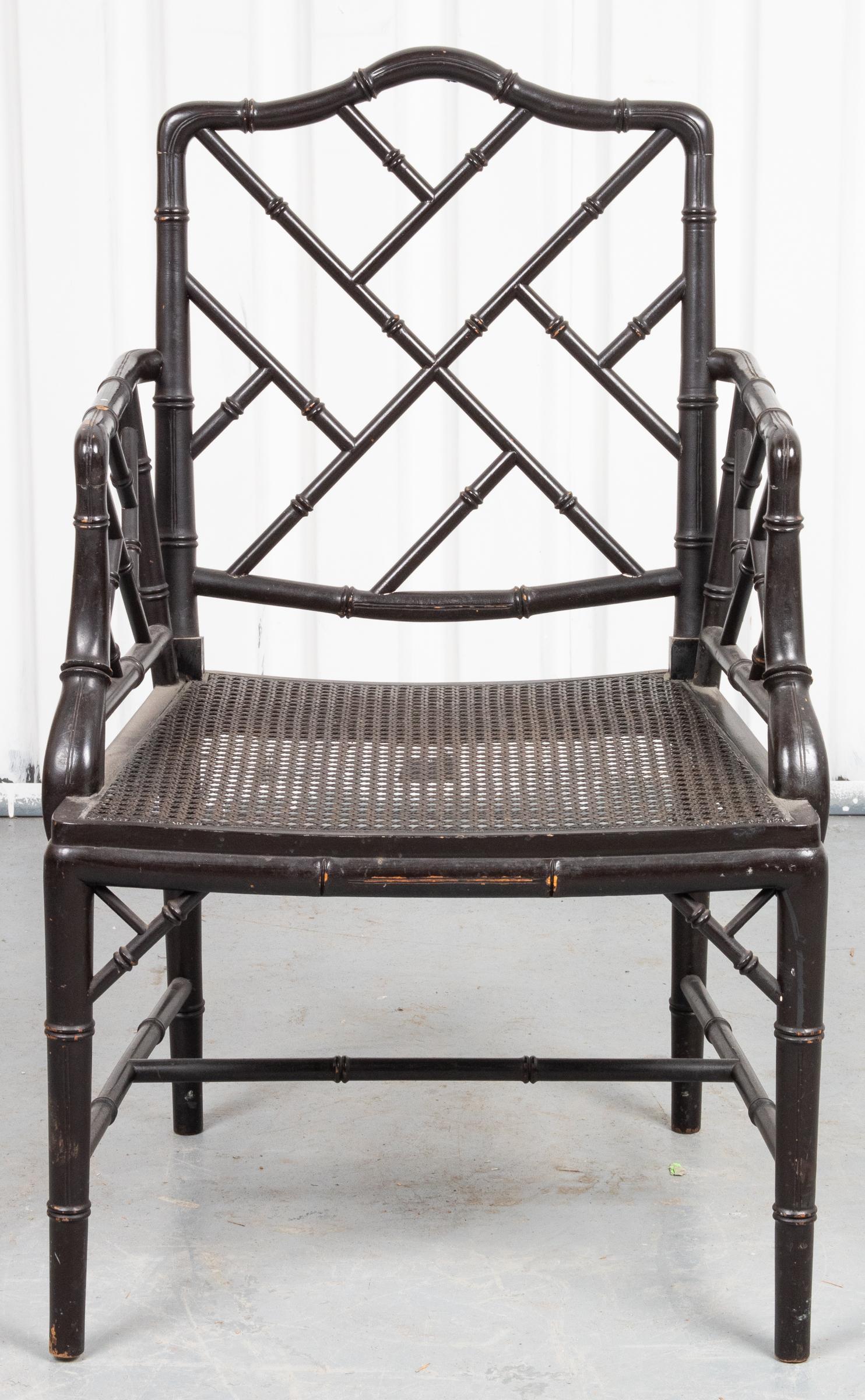 Pair of Hollywood Regency style black bamboo motif armchairs with cockpen back and caned seats. Measures: 36.5” H x 24” W x 21” D.