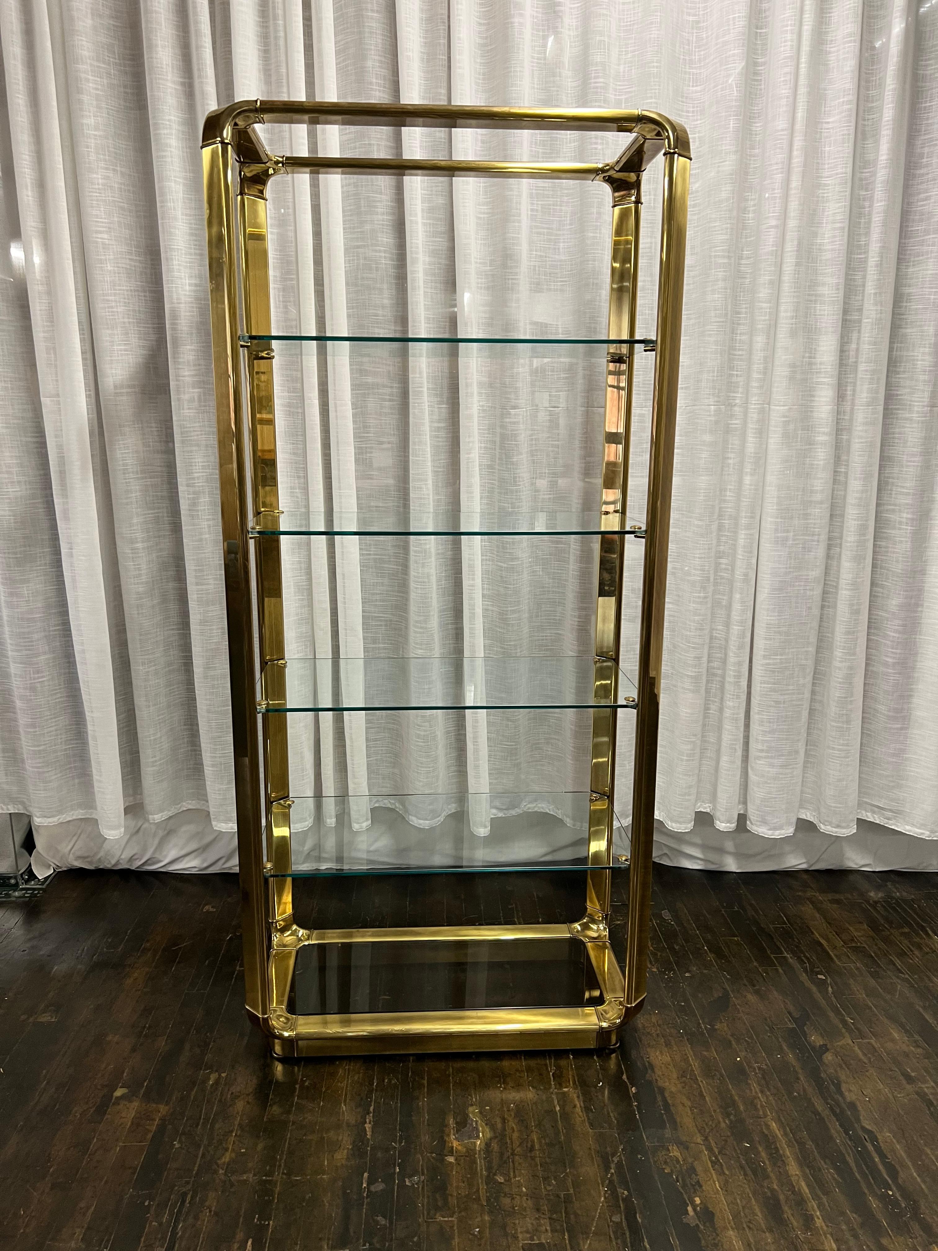 Un'eccezionale étagère in ottone e vetro di John Widdicomb di Grand Rapids, di stile Hollywood Regency, risalente alla metà del secolo scorso. L'étagère presenta una pesante struttura in ottone massiccio con angoli a cascata. Ha quattro ripiani in