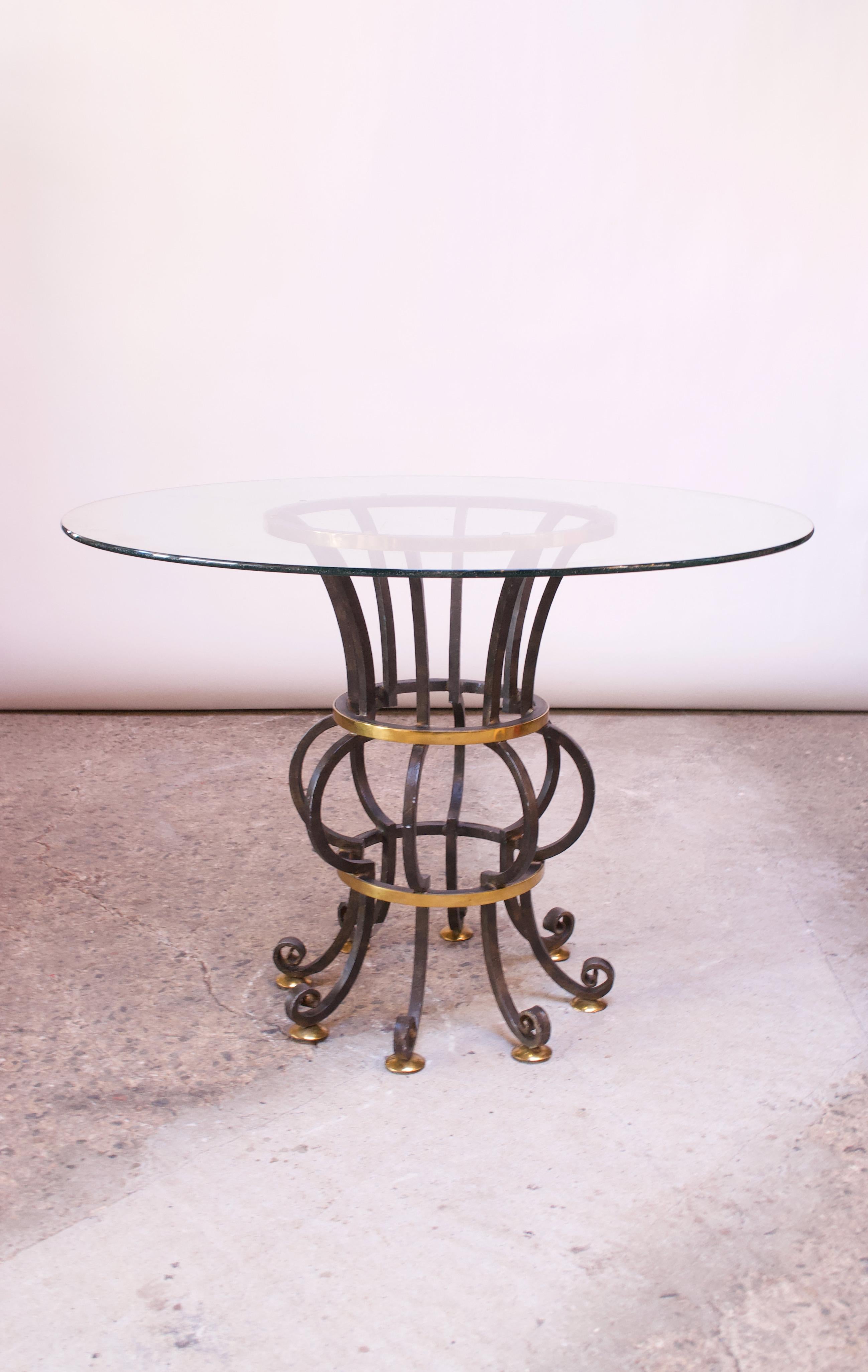 This unique table, comprised of bent / painted steel and brass, was handmade in the Philippines for Lineage Home Furnishings Inc. of North Carolina. The glass top shows wear (scratches from use), but the base is in good, vintage condition. The base