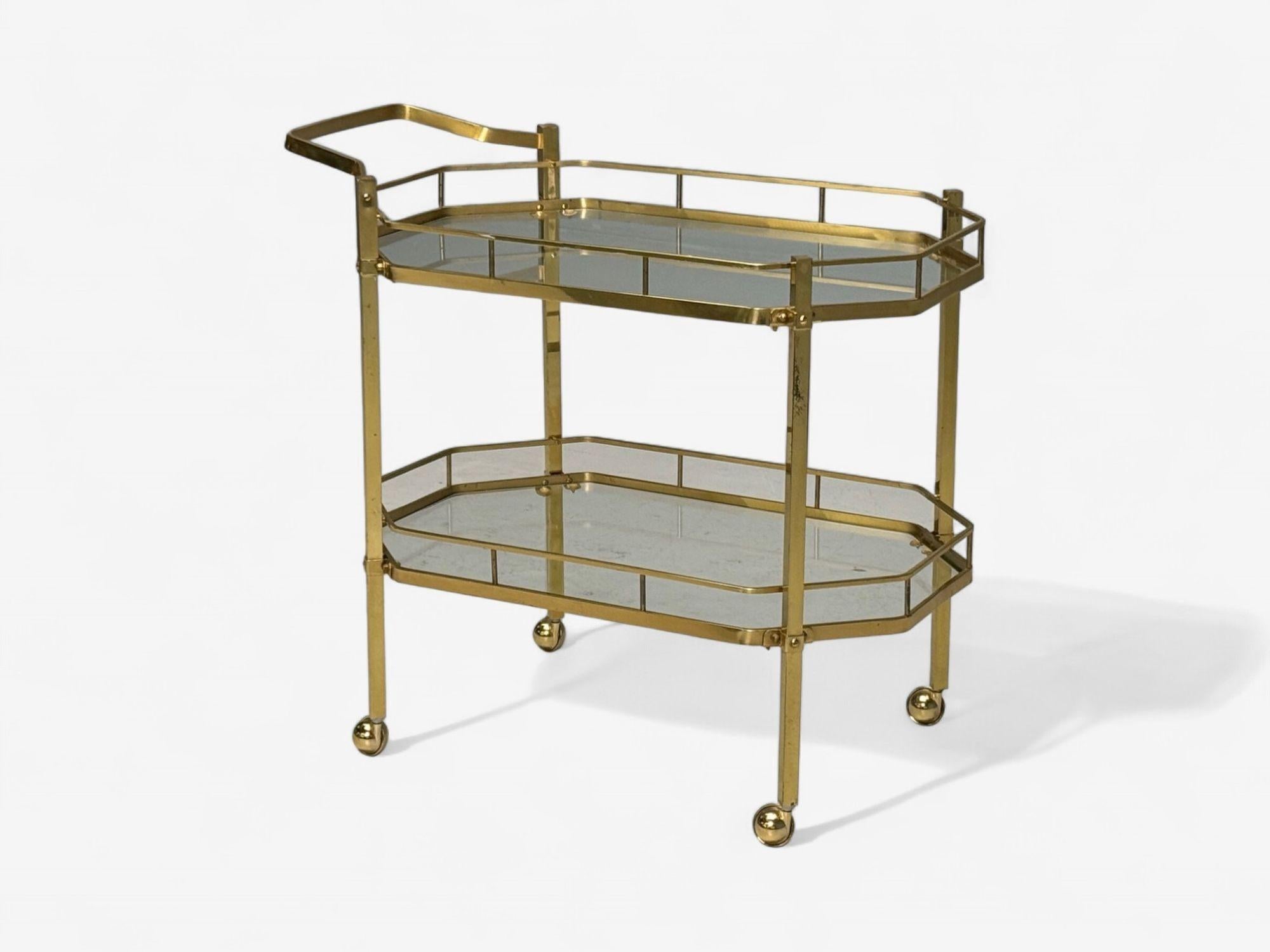 Hollywood Regency Style, Brass, Glass, Tiered Bar Cart, France, 1970s

A mid-century modern bar cart designed and produced in France c. 1970s. This example has two octagonal shaped tiers with geometric form brass gallery's and sits on four brass