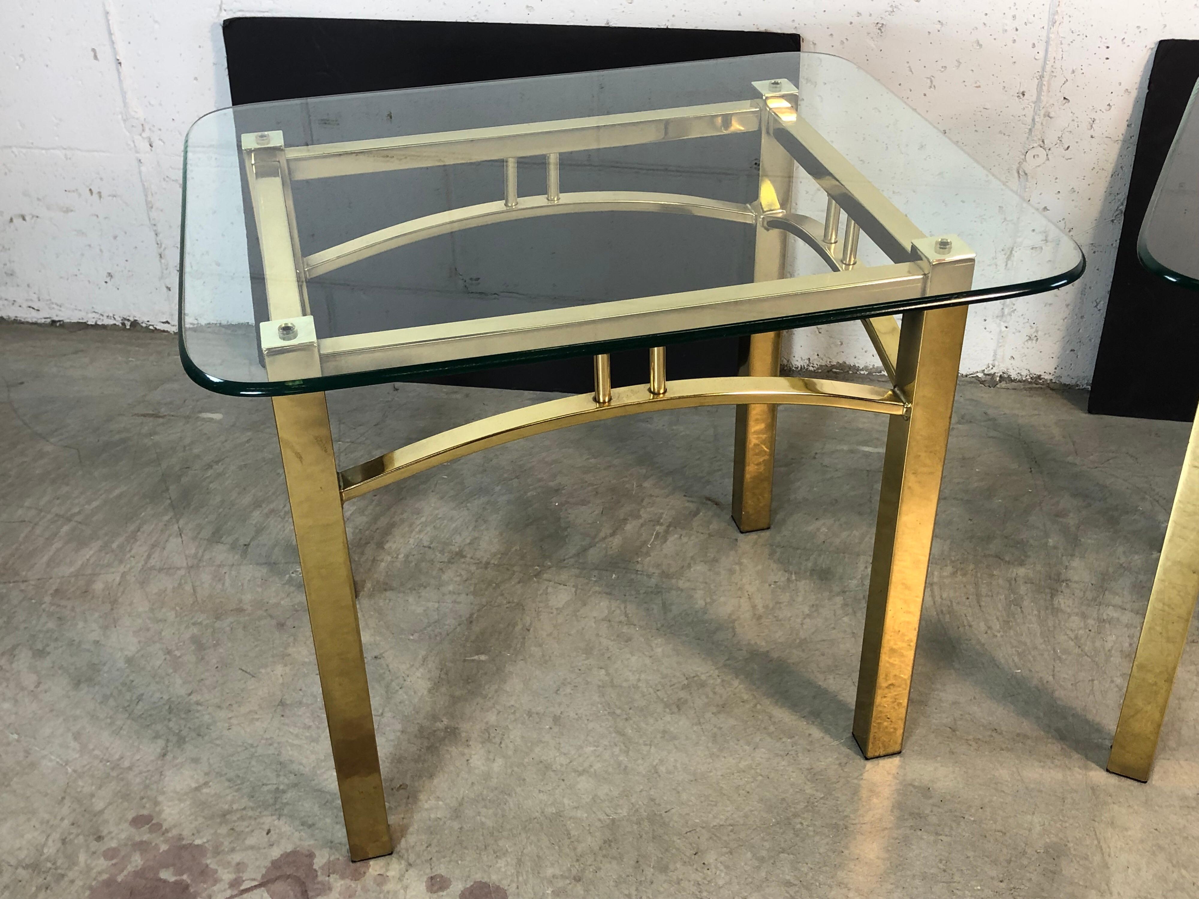 Hollywood Regency style pair of brass rectangular base side tables with glass tops. The tables are sturdy and have minimal wear to the glass. No maker’s mark.