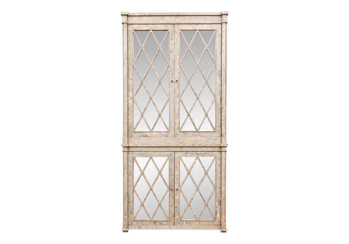 Un grande e imponente mobile in due parti dipinto in finta pietra in stile Hollywood Regency con divertenti pomelli in metallo. Il mobile presenta pannelli delle ante a specchio con motivo a diamante e rosette intagliate alle intersezioni. Le porte