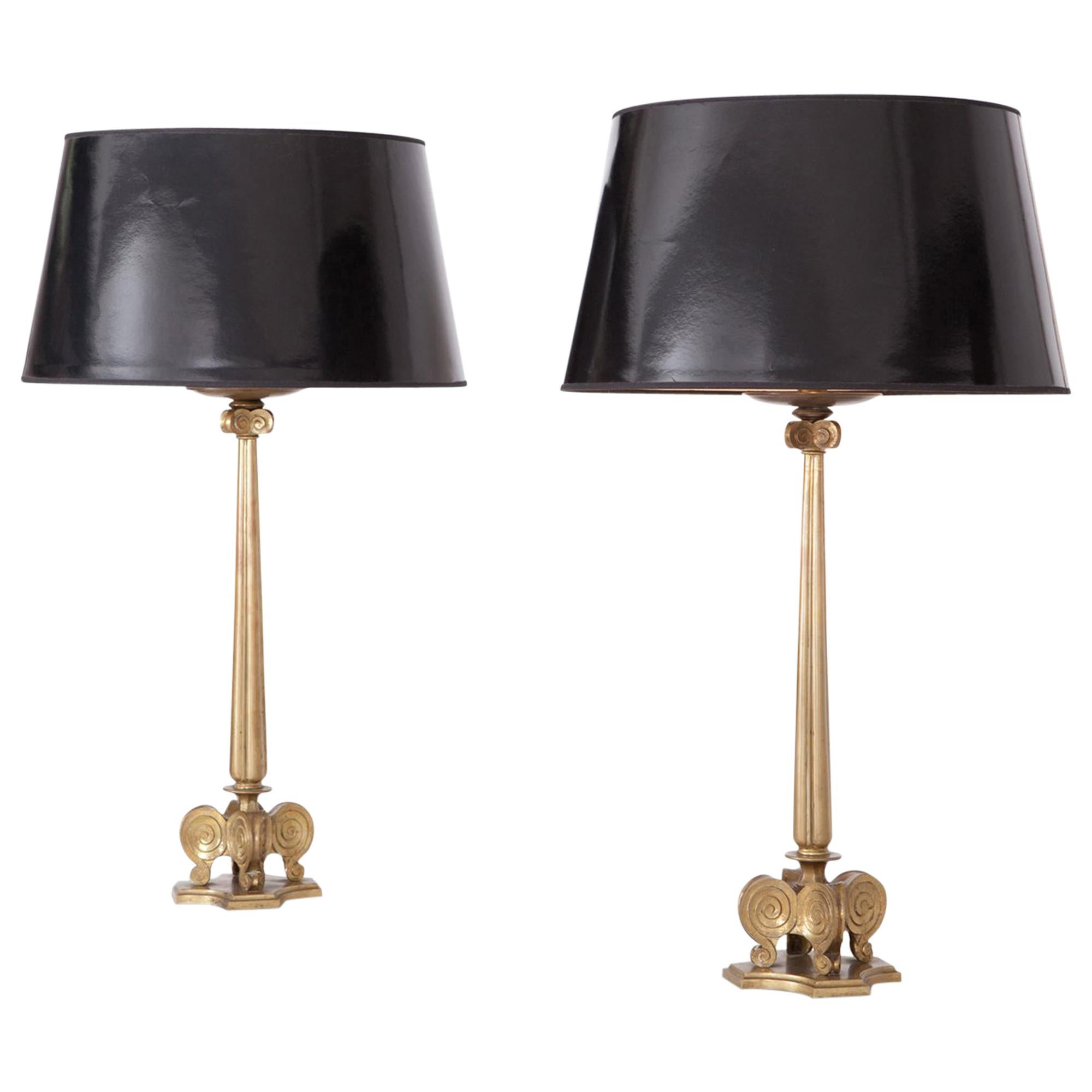 Brass Hollywood Regency style candelabra table lights, made in Italy. Set of two. 

The large brass stems are decorated with several curled shapes and holds a large glossy black shade.
  