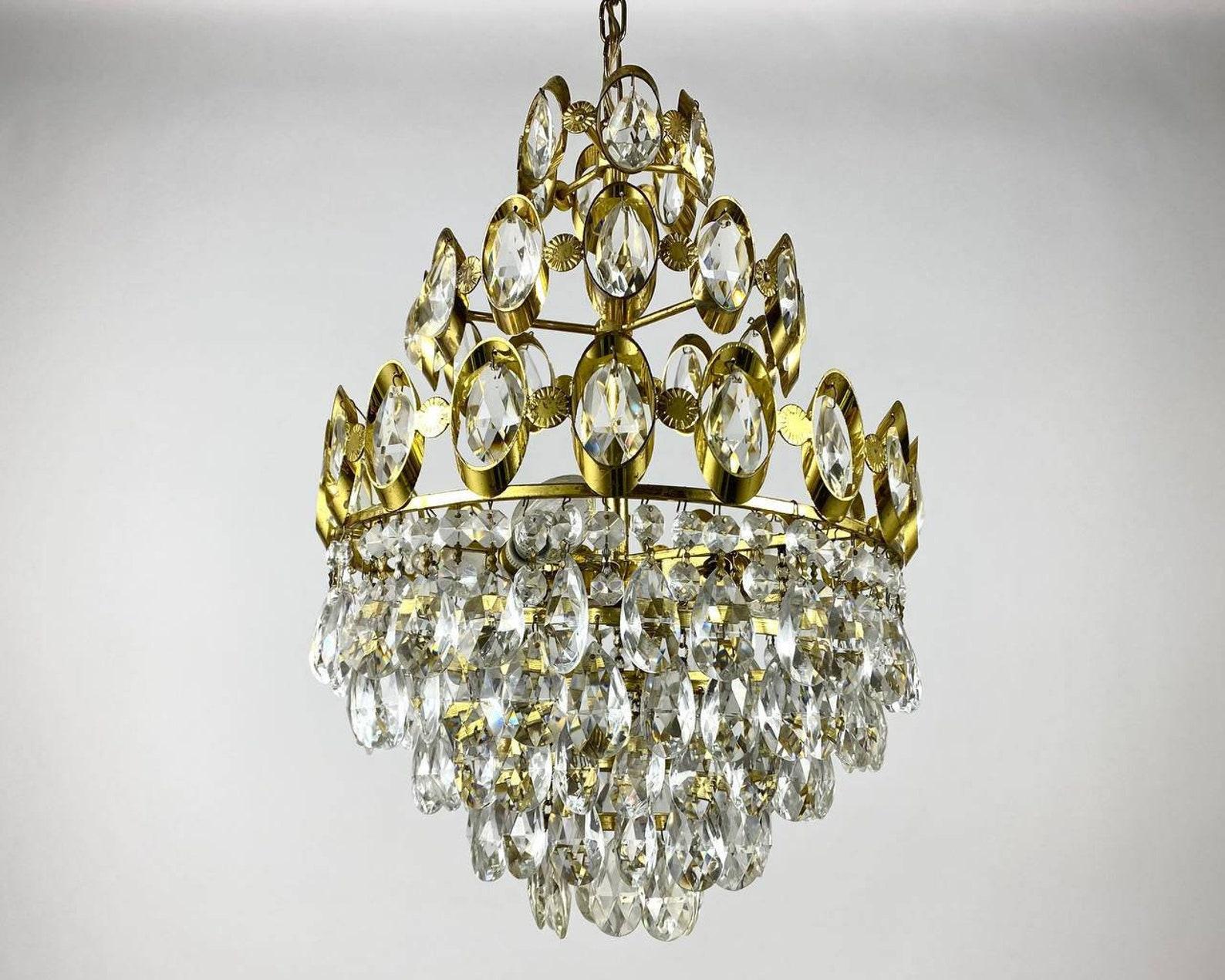 Hollywood Regency Style Crystal and Brass chandelier is the quality in every detail of the lighting fixture. 

Brass frame of gold color and crystal transparent details perfectly complement the interior of the living room.

Vintage crystal