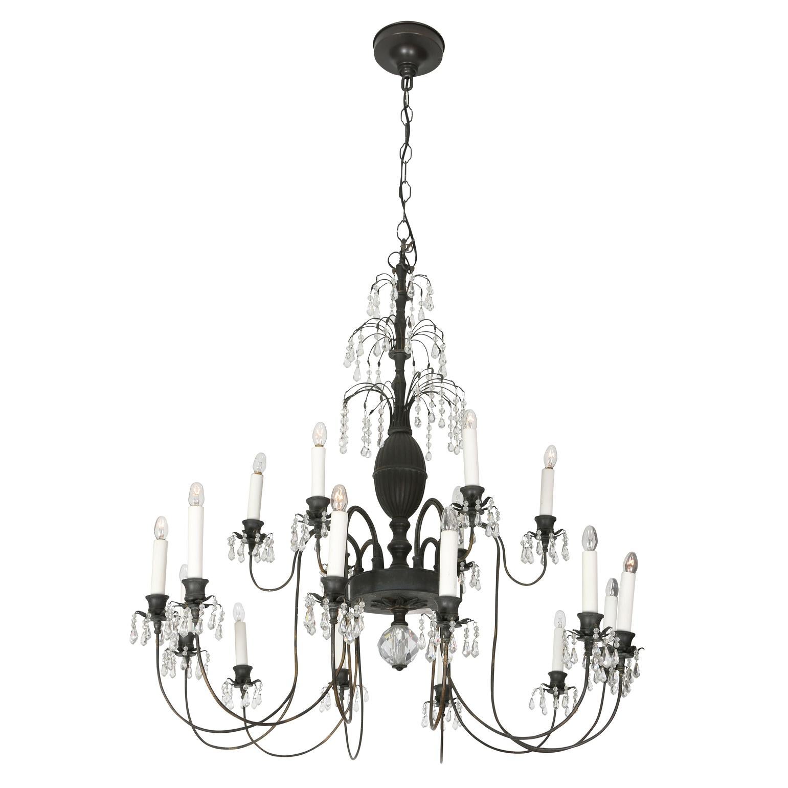 A whimsical chandelier in the Hollywood Regency style. This unique piece in bronze consists of 18 arms stemming from a center column filled with small beads and teardrop crystals. A large round crystal hands from the center. Light and airy, the