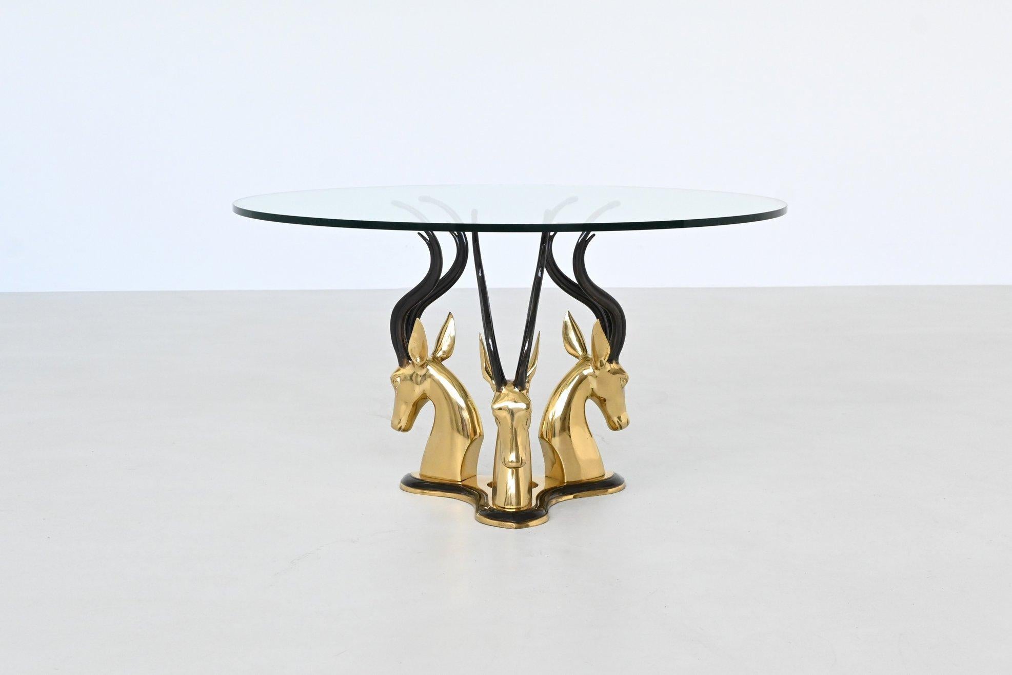 Cette table basse sculpturale d'origine française, datant de 1970, est une pièce d'apparat audacieuse dans la plus pure tradition de la Régence hollywoodienne. Elle est une célébration glamour de la forme et du luxe. La base est ornée de trois têtes