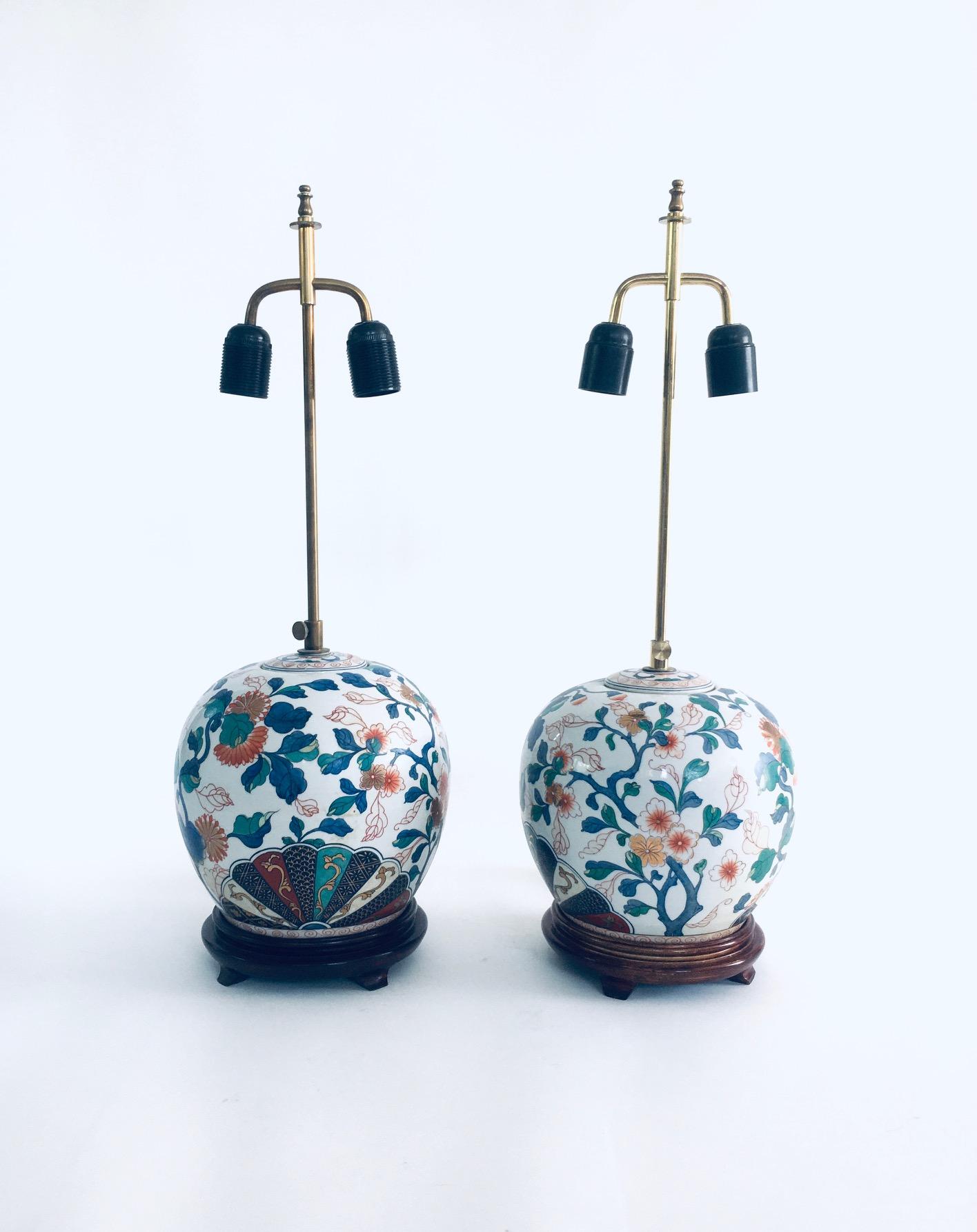 Vintage Hollywood Regency Style Chinois Design Ceramic Table Lamp set of 2. Made in China, 1960's period. Porcelain / Ceramic with hand painted floral illustrations on wood base with brass lamp fittings that will take 2 E27 light bulbs. They are