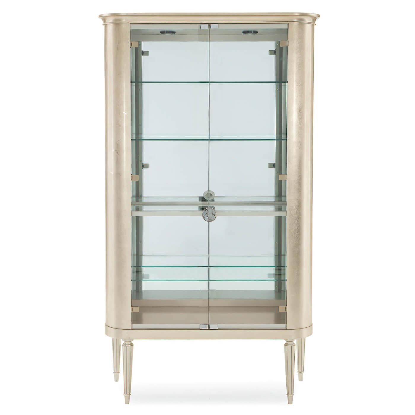 A striking showcase piece inspired by both 18th-century French Louis XVI design and the sleek sophistication of Art Deco. Its graceful curves are highlighted by a Soft Silver Leaf and Soft Silver Paint finish, enhancing any refined interior. Behind