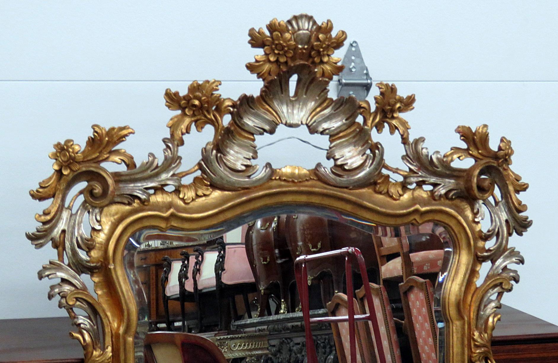 Louis XV style wall mirror with distressed gilt frame and beveled glass.