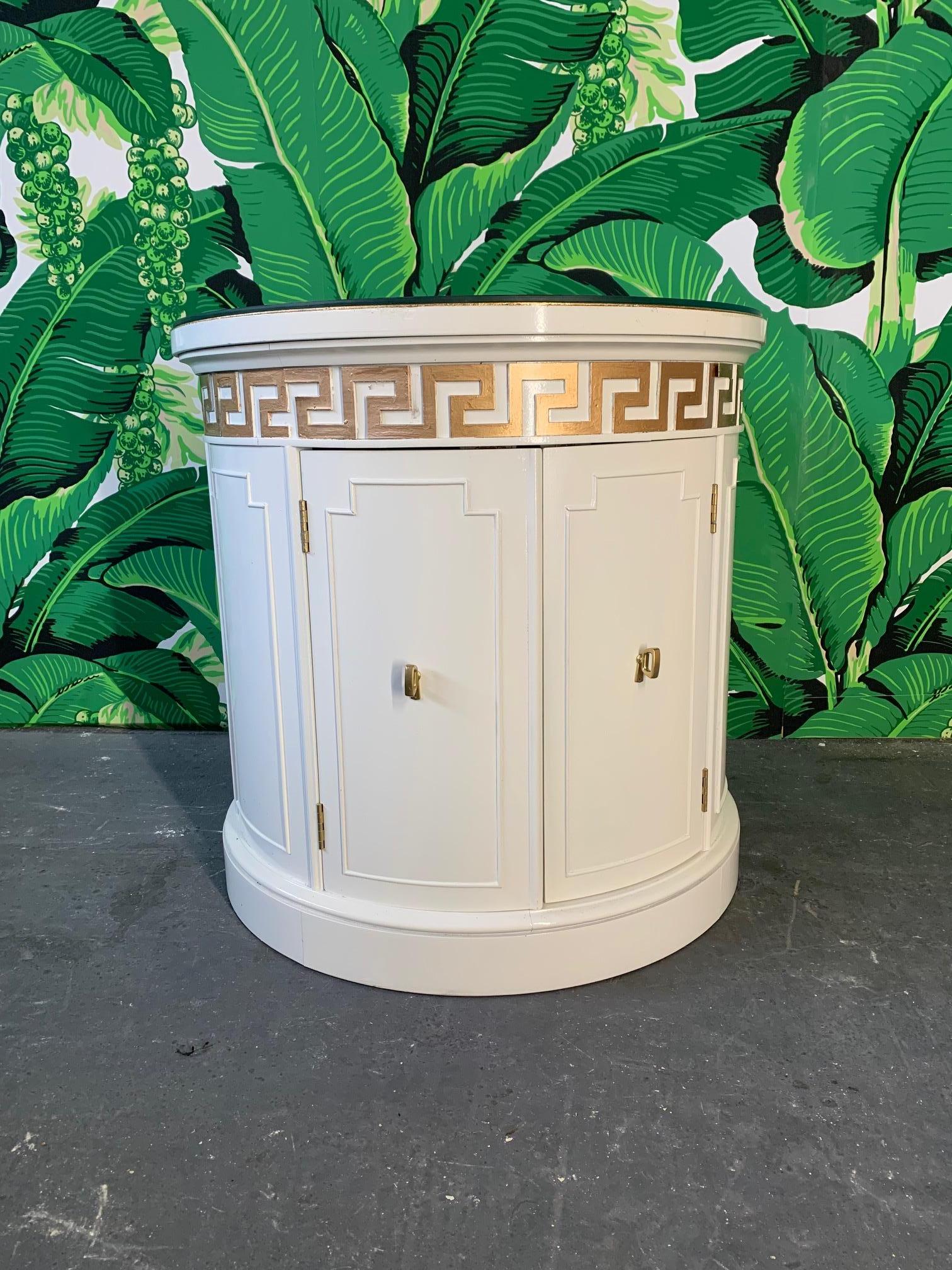 Pair of drum tables feature new high gloss white lacquer finish, gold leaf tops, and Greek key detailing. Glass tops protect gold leaf finish. Double doors reveal storage area. By Thomasville Furniture, circa 1964. Very good condition with minor