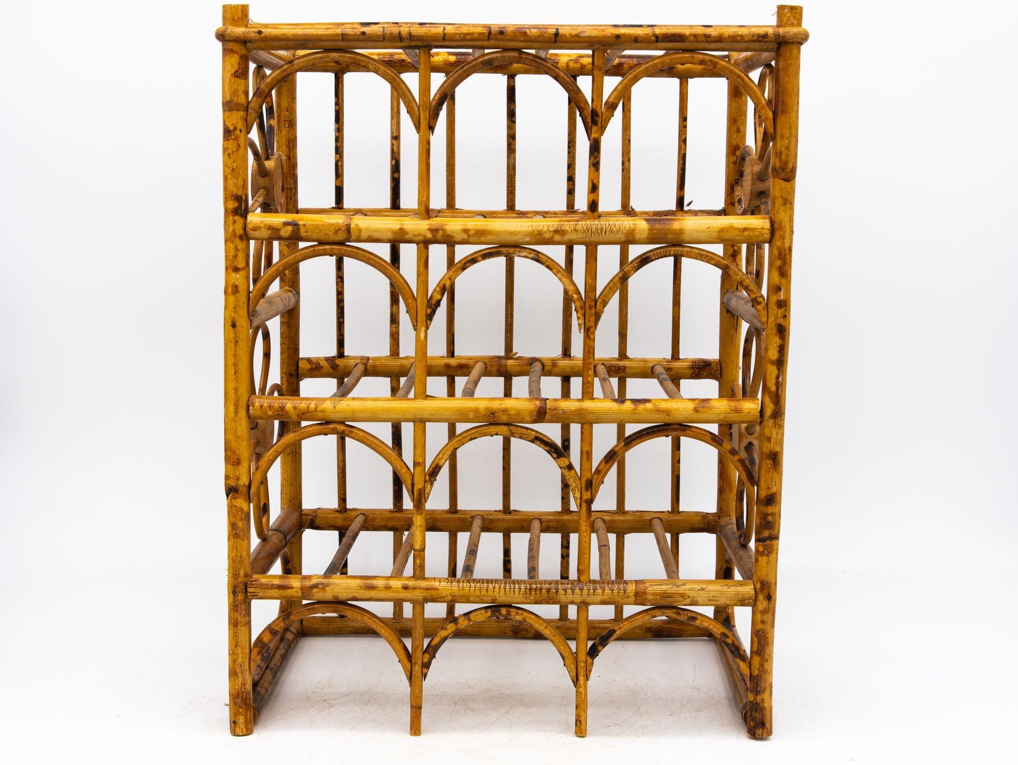 This vintage Hollywood Regency tortoise bamboo rattan wine rack is a charming and practical addition to any home. It features four shelves that can hold a total of 12 bottles, with elegant four-petal rattan flowers adorning the sides. The sturdy