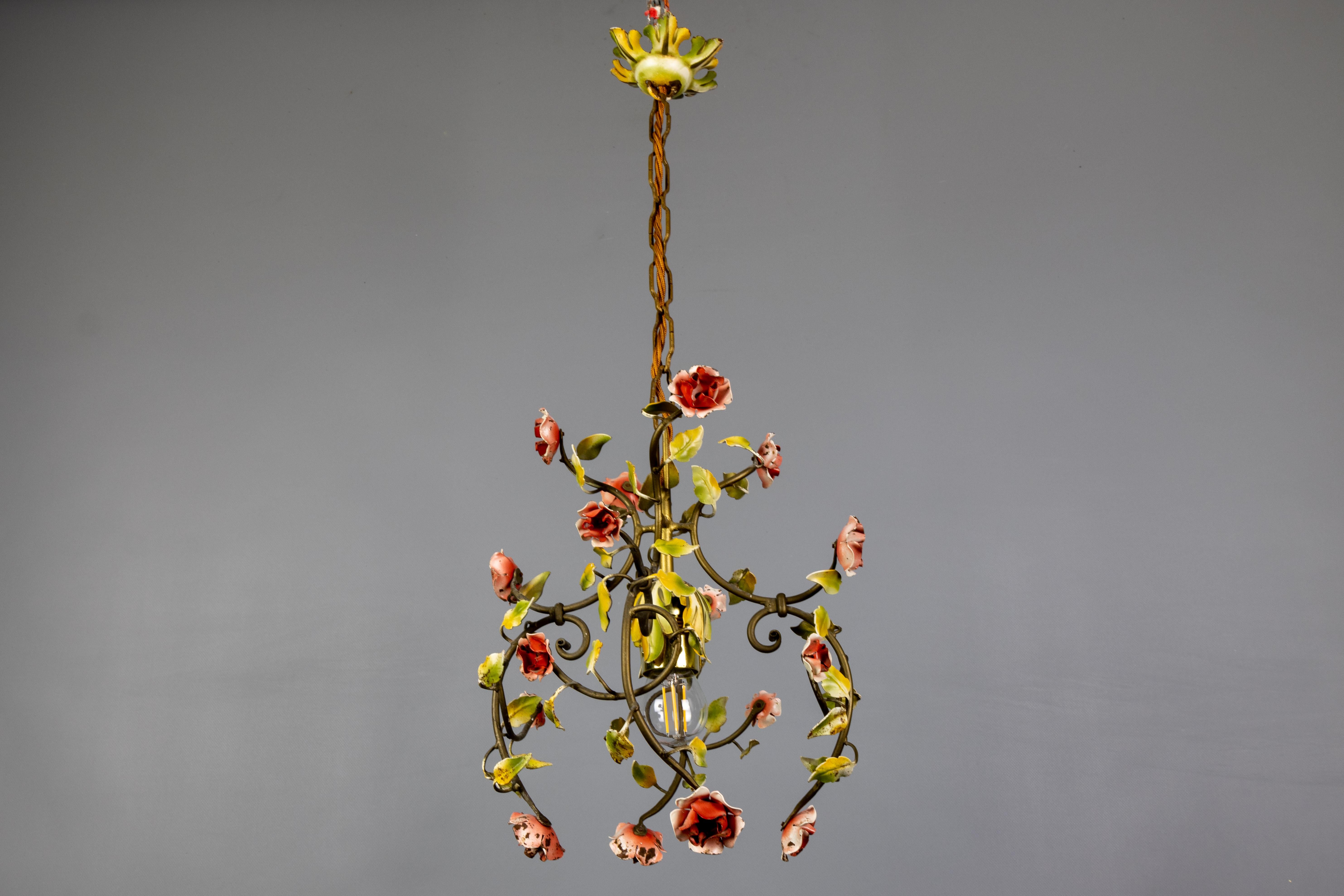 Lampadario a una luce in metallo verniciato color pastello in stile Hollywood Regency, Francia, anni '50 circa.
Presenta una splendida cornice in metallo ornata da fiori nei toni del rosa e del rosso, completati da foglie verde chiaro. Il lampadario
