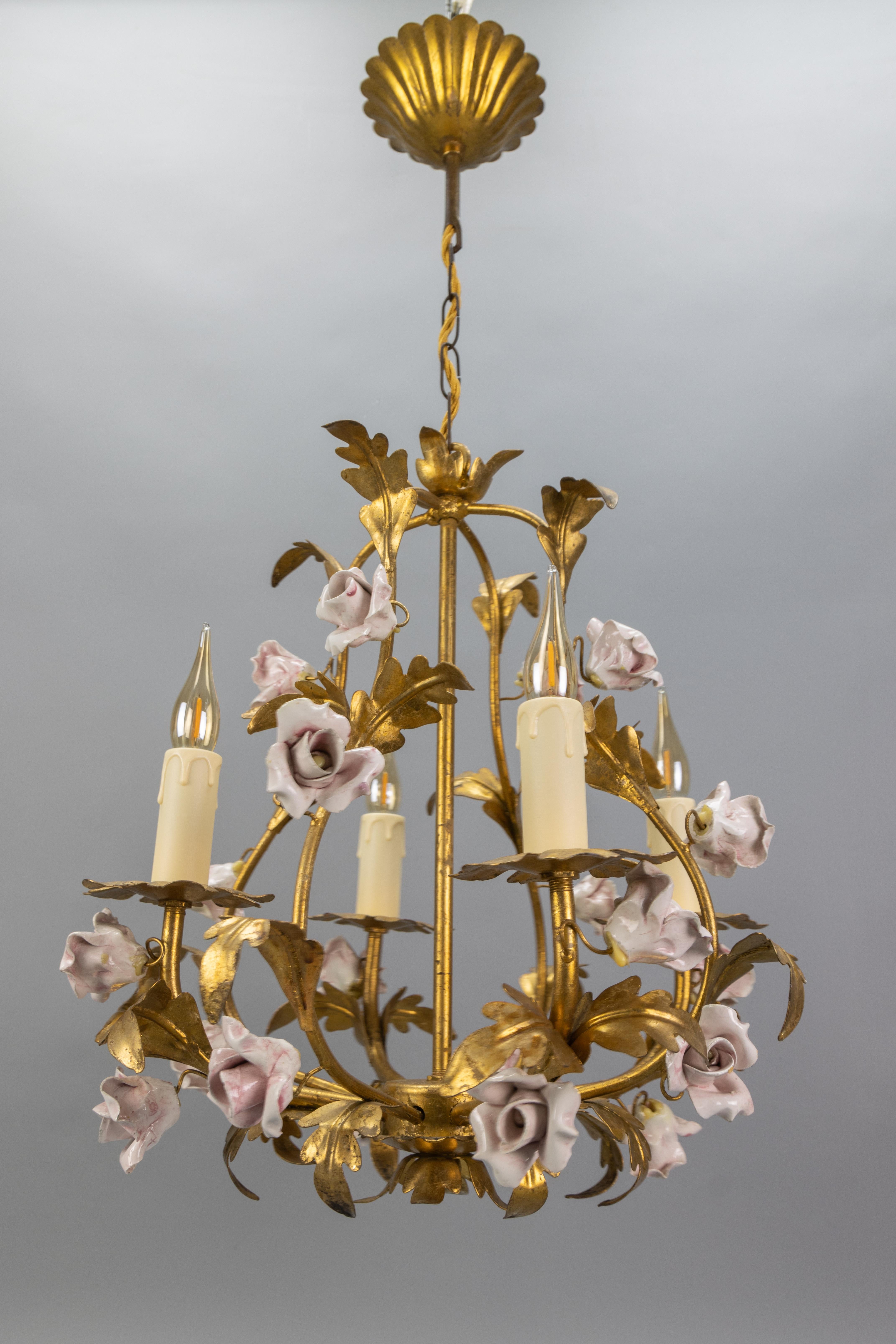 Vergoldetes Metall und rosa Porzellanrosen im Hollywood-Regency-Stil, Italien, ca. 1970er Jahre.
Dieser atemberaubende vierflammige italienische Kronleuchter aus vergoldetem Geschirr hat ein Vogelkäfig-Design mit einem Rahmen/Armen, der von