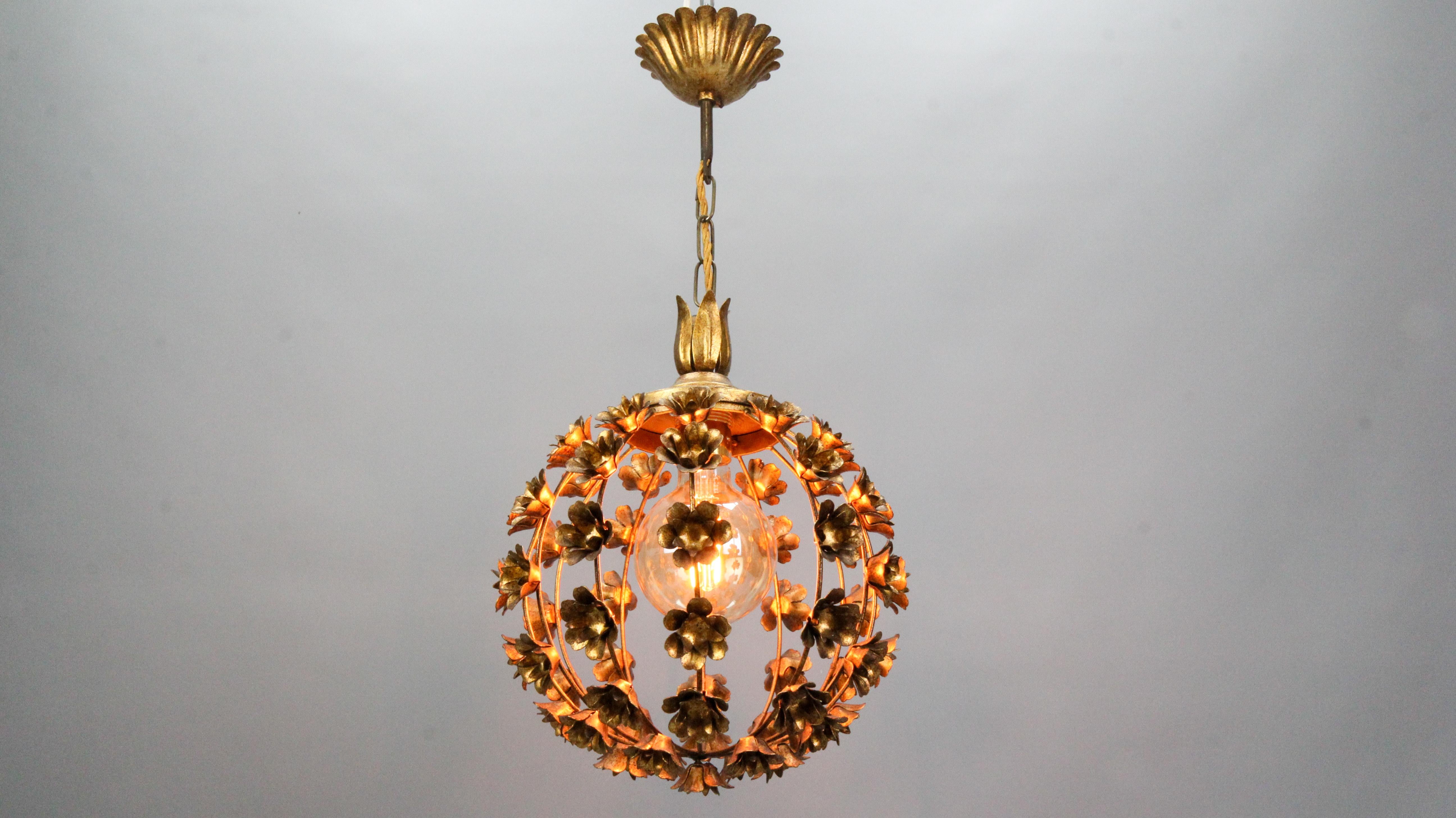 Hollywood Regency style gilt metal floral spheric pendant light, Italy, circa the 1970s.
This beautiful gilt metal pendant chandelier features a sphere-shaped frame decorated with flowers that surround the single light with a new socket for an E-27