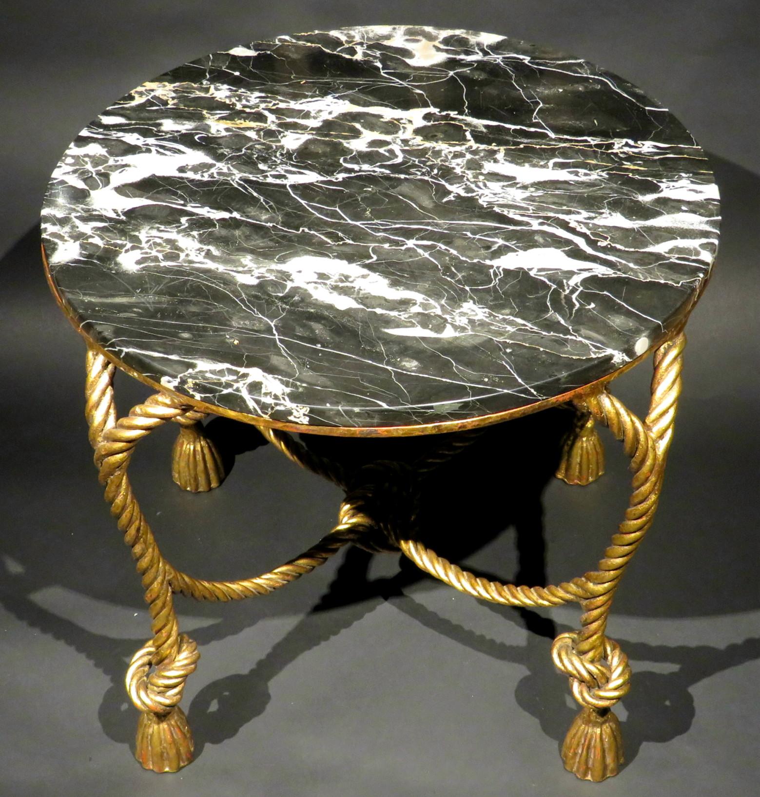 A highly decorative mid 20th century marble topped coffee table / side table, showing a circular mottled black & white marble top resting upon its conforming gilt metal frame styled in a faux rope & tassel design. The underside of each foot stamped