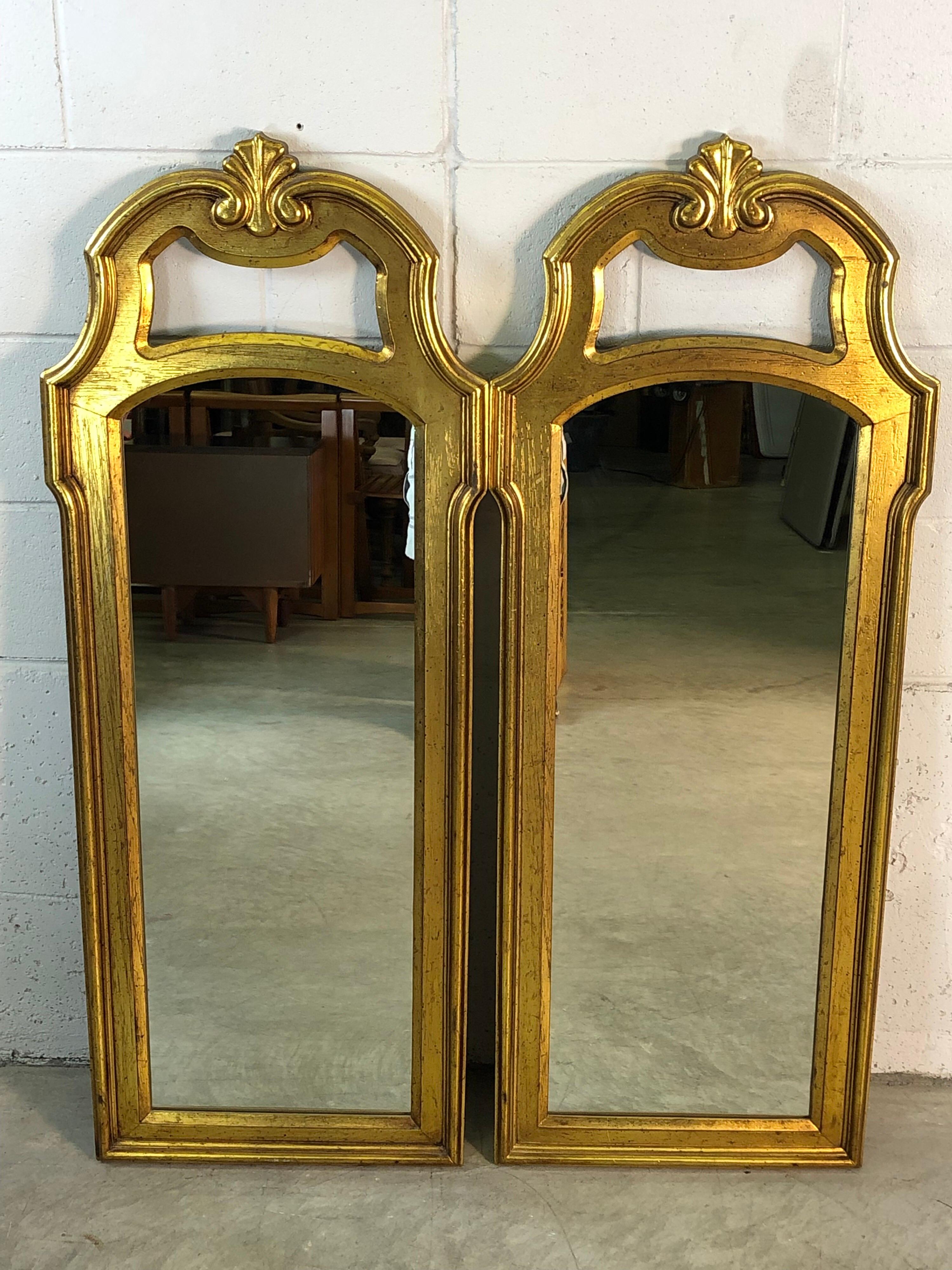 Hollywood Regency style pair of gold wood painted wall mirrors. The gold has small flecks of black in the paint. The mirrors are by Drexel Furniture Co and are in excellent condition. Hanging hooks are included.