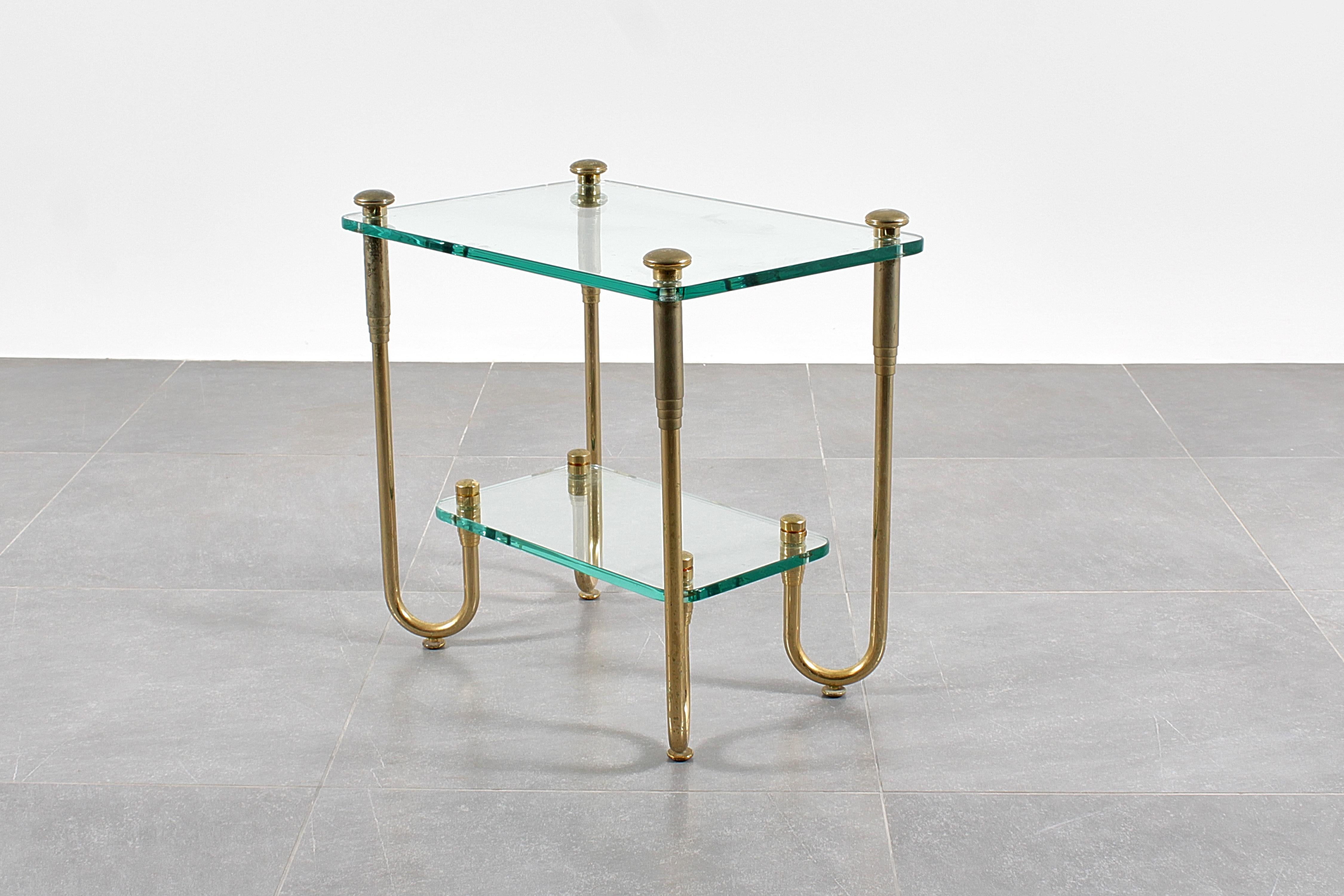 Very beautiful two-tier side table in Hollywood Regency style, with thick Nile green glass tops supported by four imposing bent brass tubular legs. Italian production from the 70s.
Wear consistent with age and use.