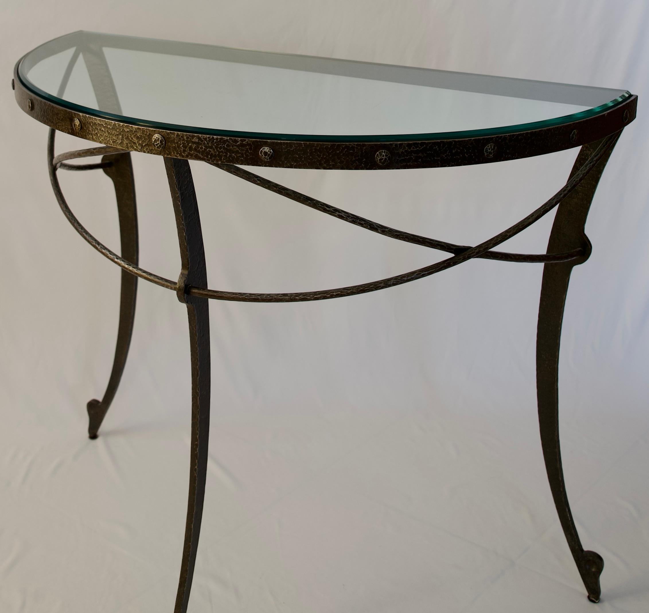 A fine quality Hollywood Regency style half moon or demilune console table with beveled glass surface and handsome wrought iron base. The semi circle beneath the top is adorned with gorgeous details. 

This beautiful console table will define a