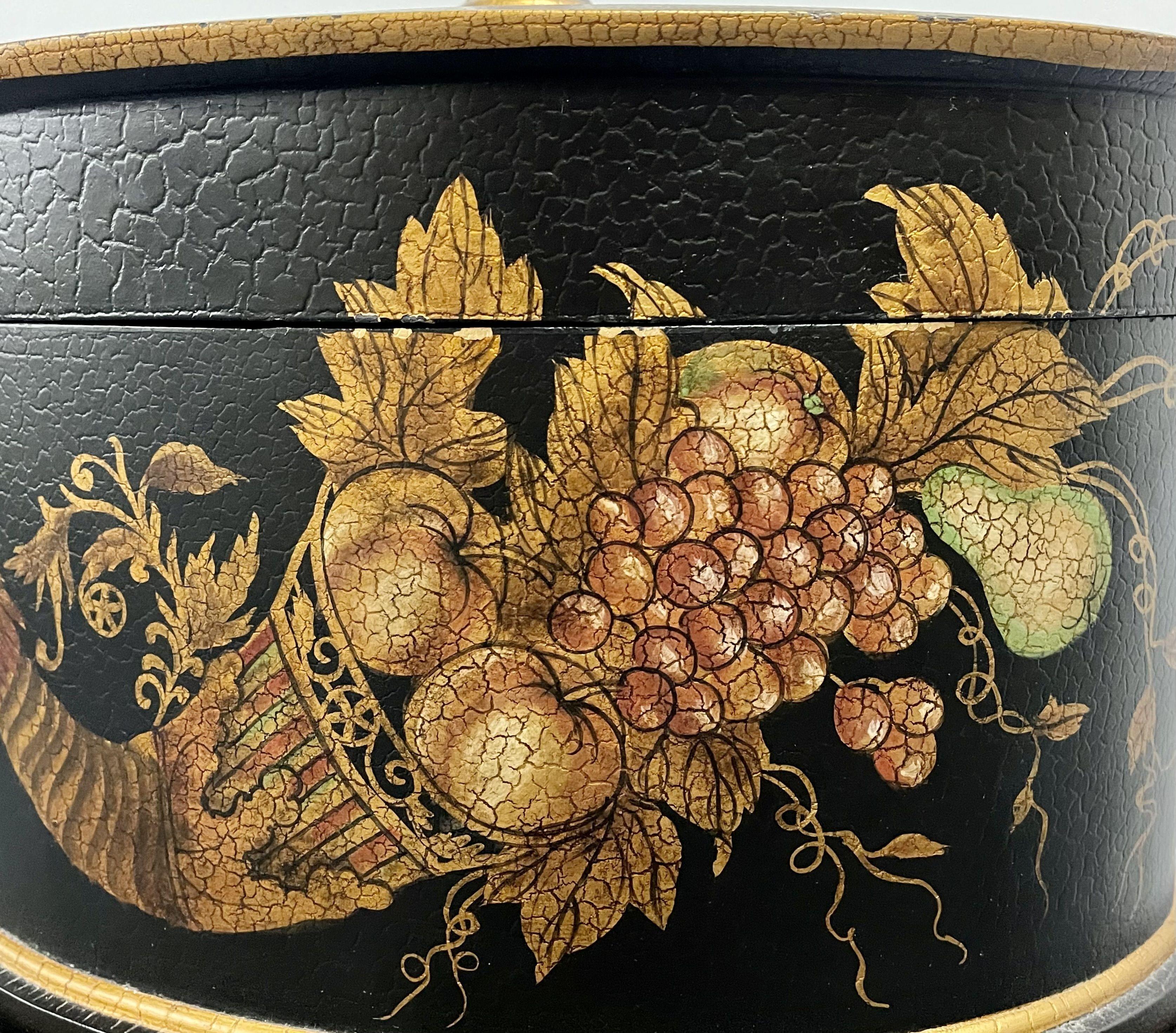 Hollywood Regency Style Lidded Casket Box on Stand. An ebony stand or end table supporting a transfer decorated lidded box or bowl. Stand itself measures 12 inches high, 16.5 wide and 16 inched deep.
