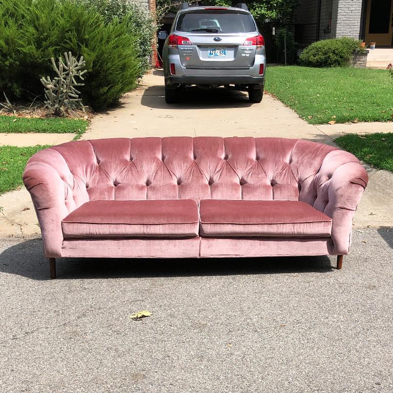 Hollywood Regency style long pink or mauve vintage tufted sofa with two cushions. A beautiful piece to add interest to any room. The arms of this sofa are slightly curved outward. The back has beautiful tufting with matching covering buttons of the