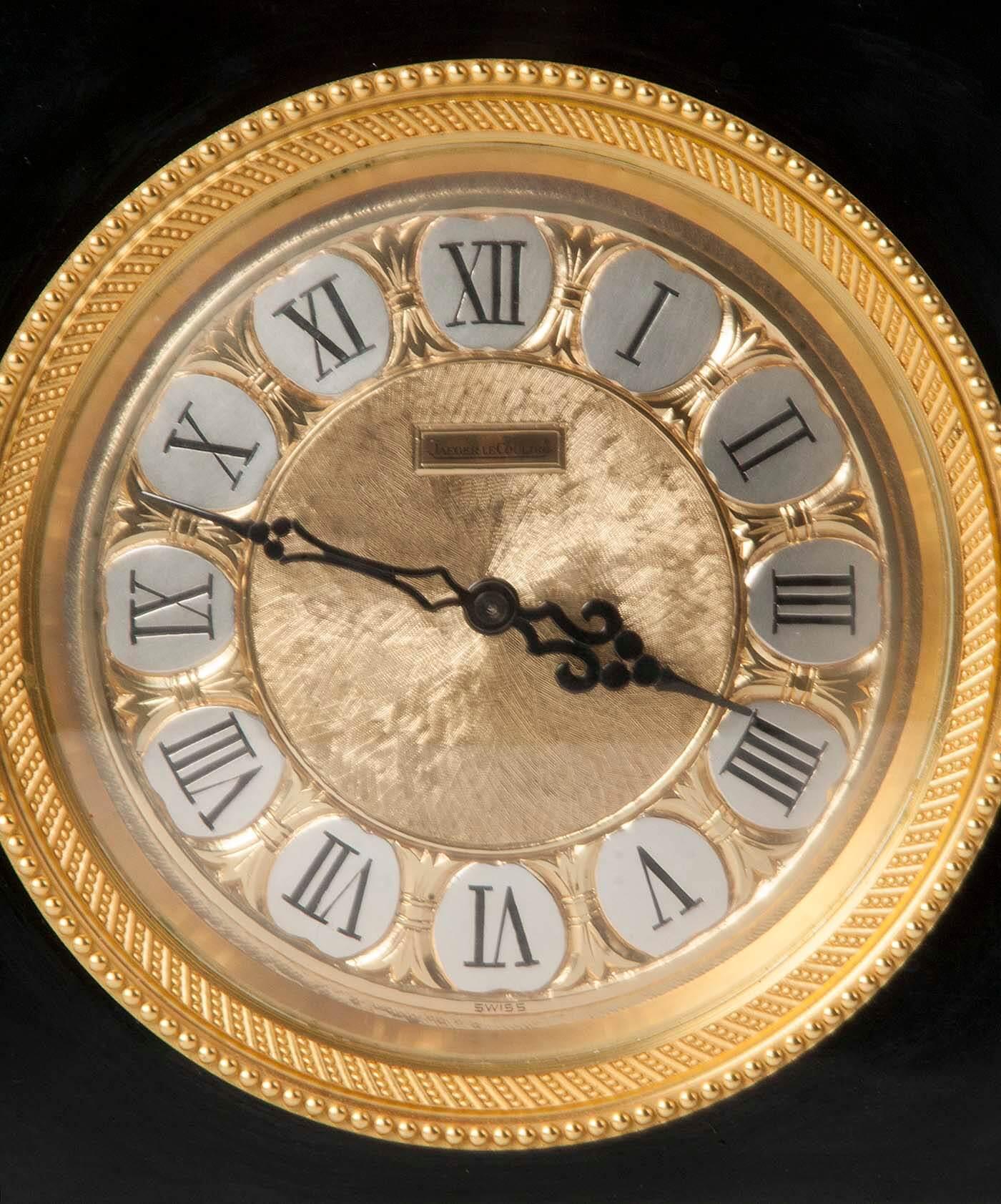Beautiful and chic clock from the famous Swiss Jaeger LeCoultre. The case is made of black lacquered zinc. Bronze dial with enamel numbers. The outer edge is fire gilt bronze.

The timepiece runs through an escapement system. Also called anchor