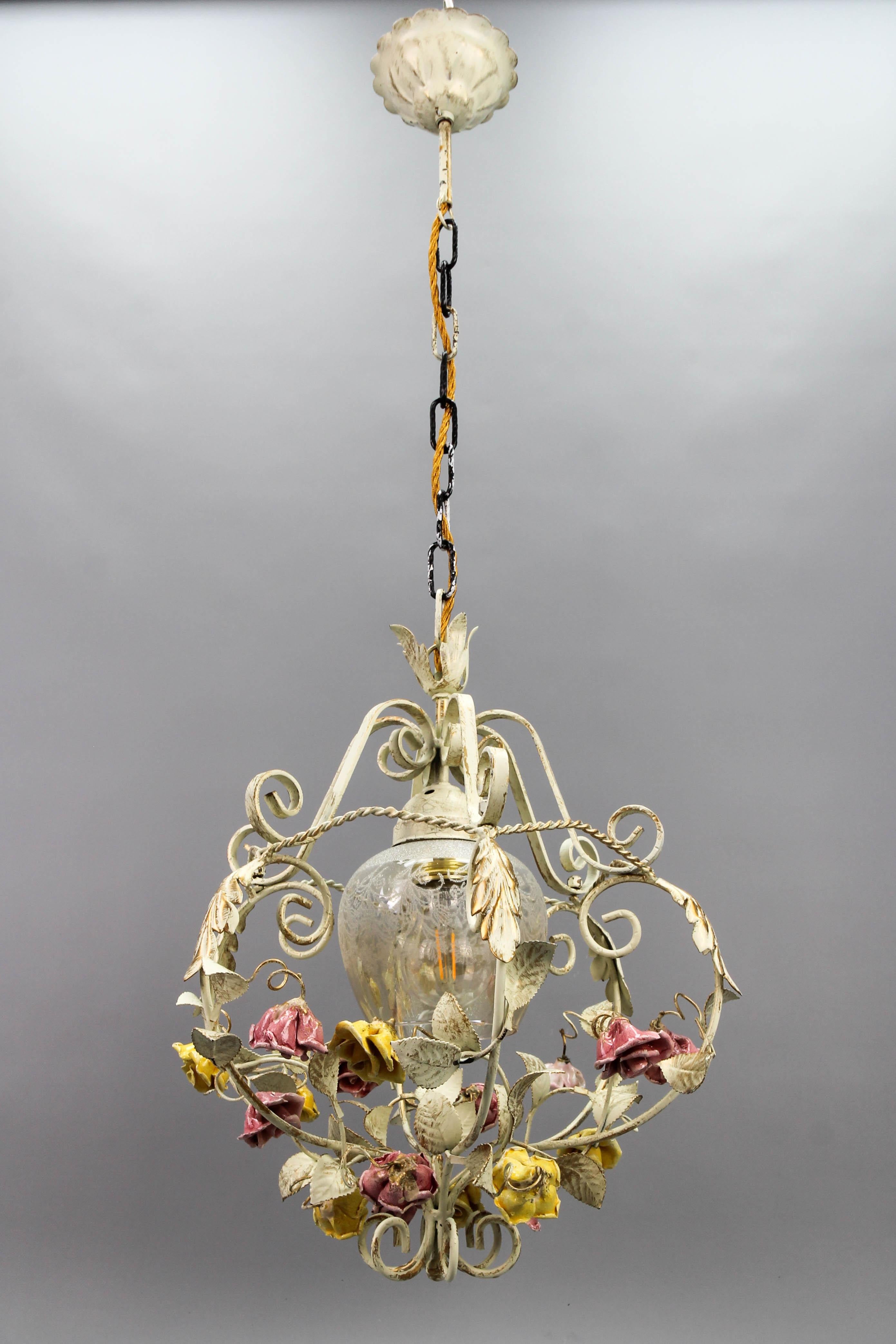 Hollywood Regency style metal and glass chandelier, from circa the 1970s, Germany.
A beautiful metal single-light chandelier from the circa 1970s. The light fixture painted in pastel tones with golden accents is adorned with leaves and beautifully