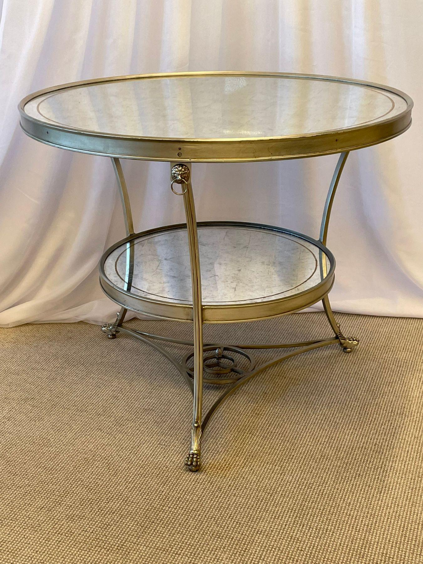 Hollywood Regency style Mirrored Gueridon, center table. 

A sleek and stylish Silver gilt gueridon having Lion head ringed tri pod base leading to claw feet. The shell having a lower and upper sliver gilt decorated mirror.

SXX.