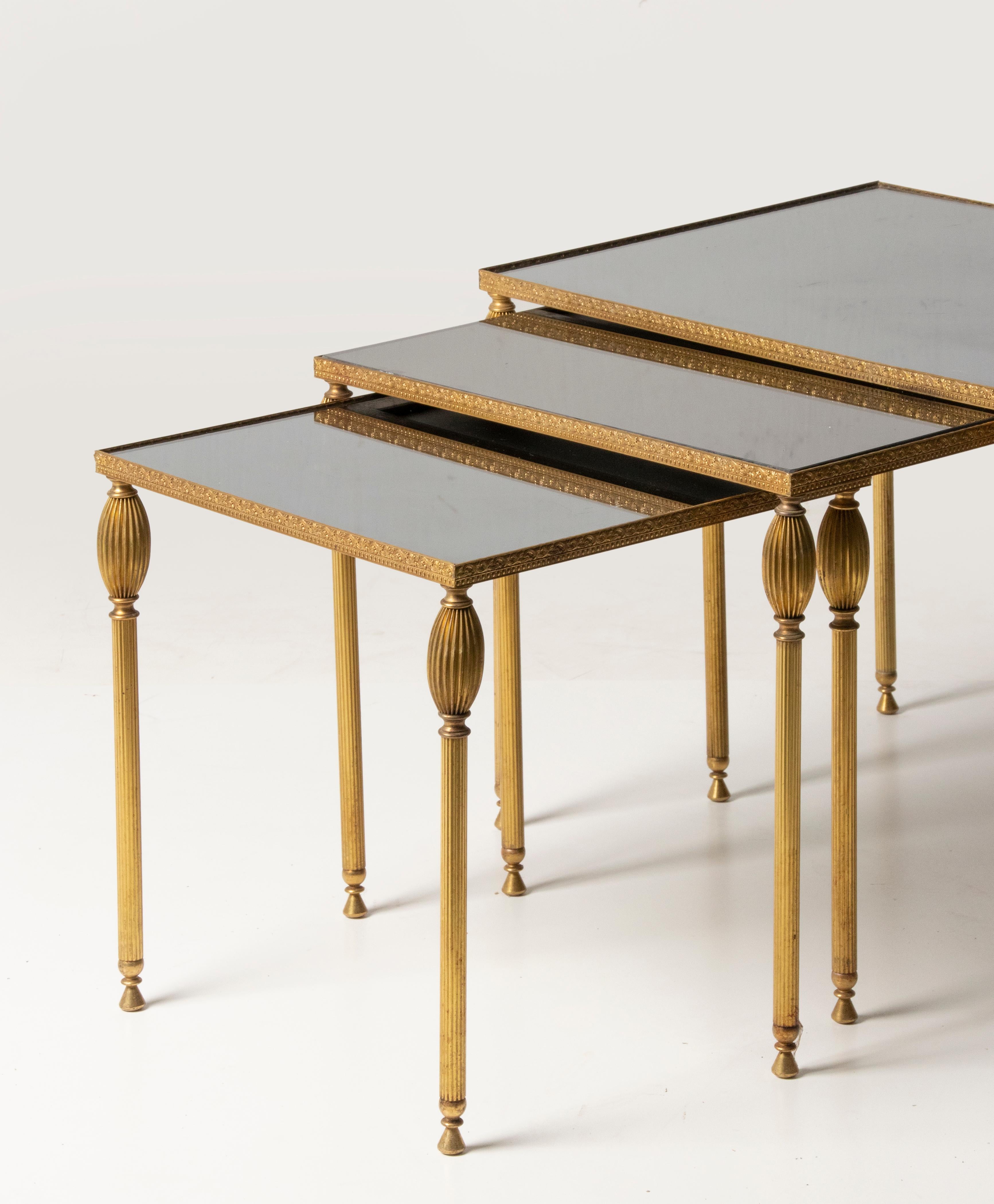 Un ensemble de trois tables d'appoint modernes du milieu du siècle. La base est en métal de couleur cuivre. La garniture en relief est en cuivre. Plaques de verre fumé noir sur le dessus. Les lunettes sont en bon état, quelques petits signes