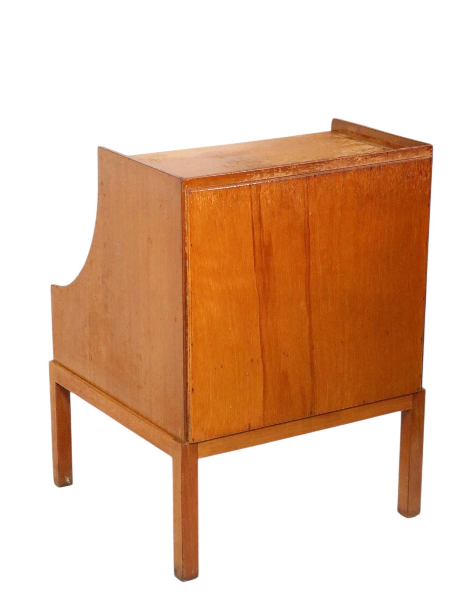 Rare Hollywood Regency style nightstand designed by Tommi Parzinger, for Charak Modern. This stand features a dramatic scoop form case with an open storage space over a pull out drawer. This example is structurally sound and sturdy, the finish shows