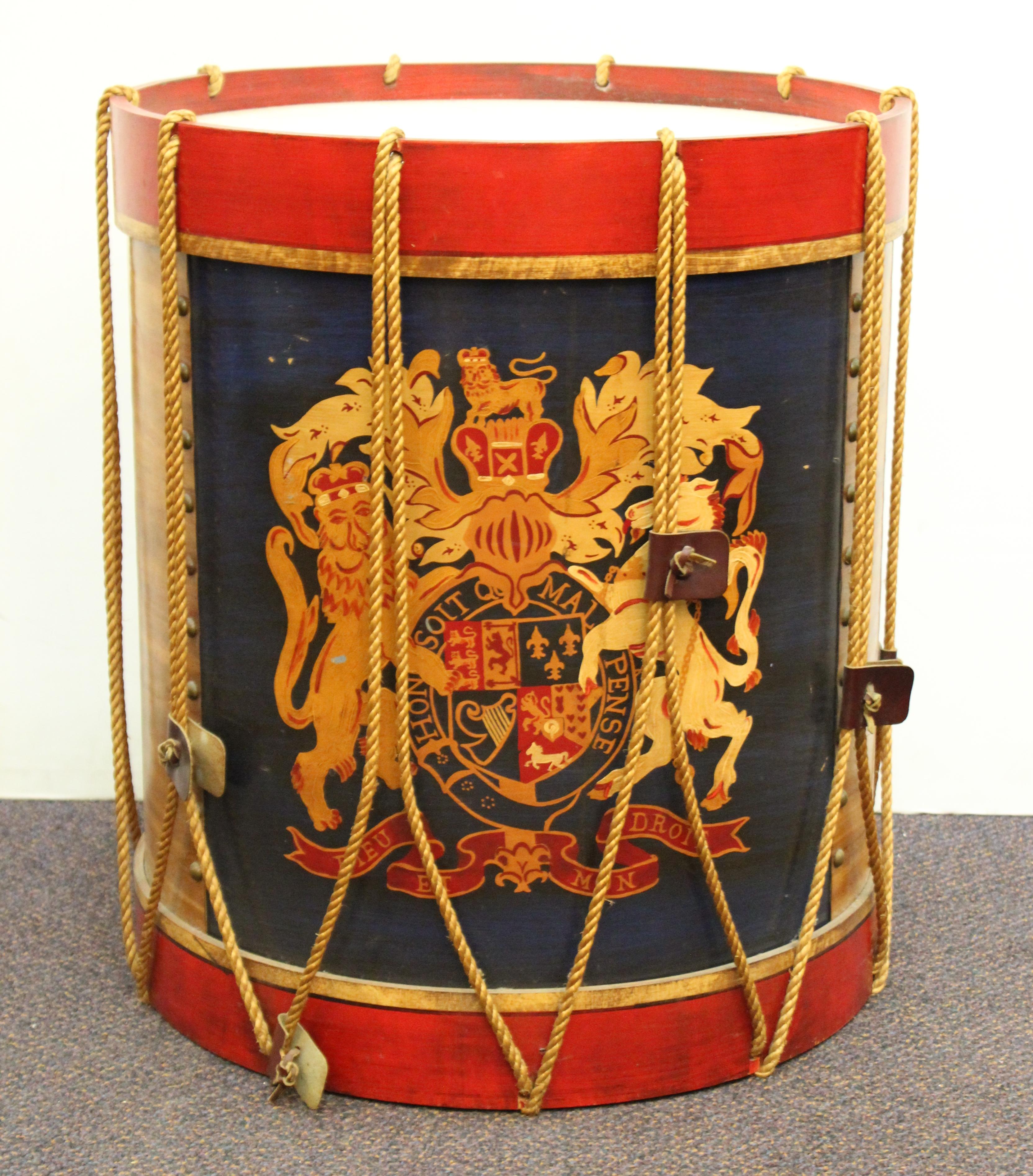 Hollywood Regency style pair of side or end tables in the shape of regimental British drums. The pair has cord and leather detailing and hand-painted British coat of arms. Some of the leather detailing is missing and a few of them are missing. In