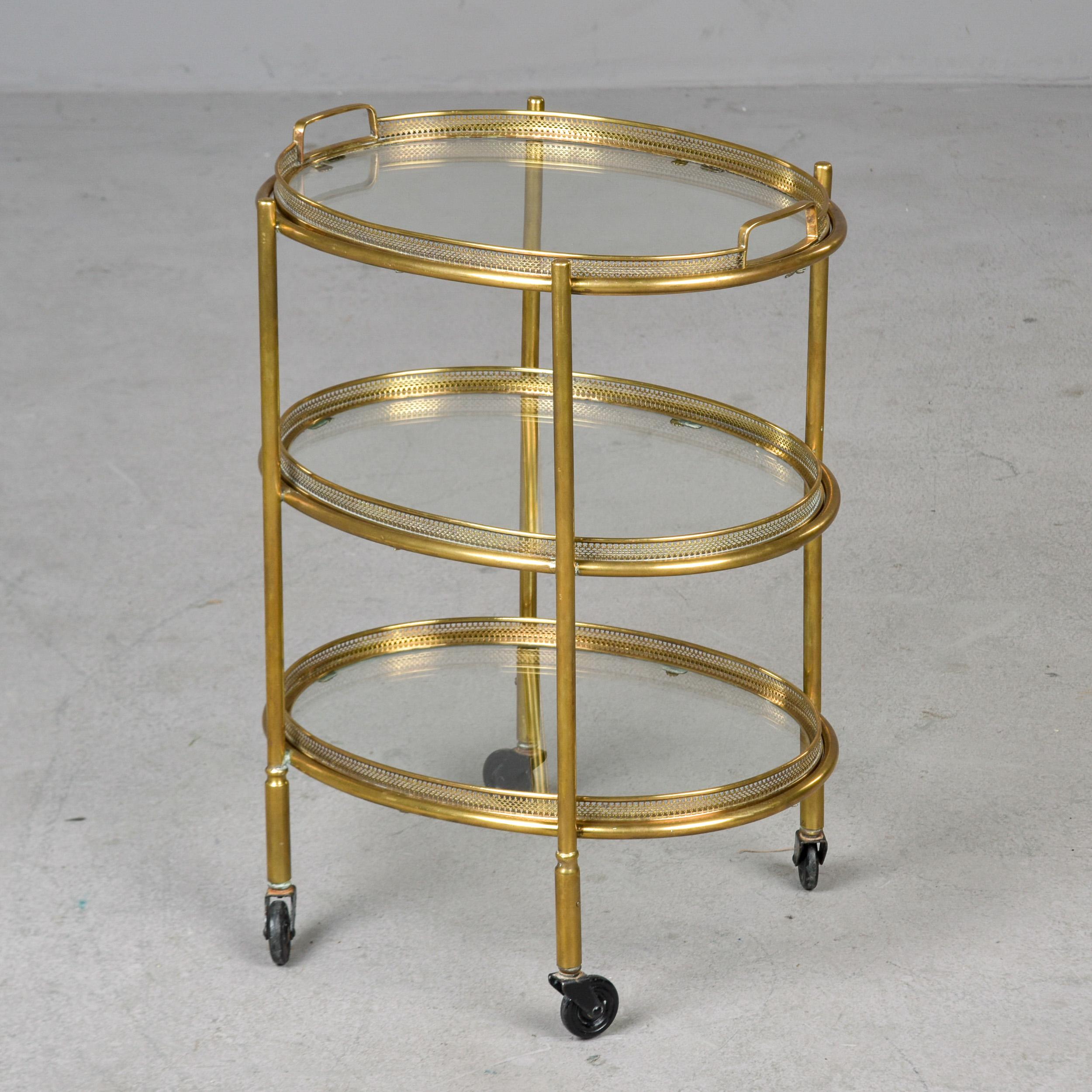 Found in Italy, this three tier trolley dates from the 1950s. This three tier oval side table on casters features removable glass and brass trays. The top tray features handles and the two lower tiers are removable brass and glass trays without
