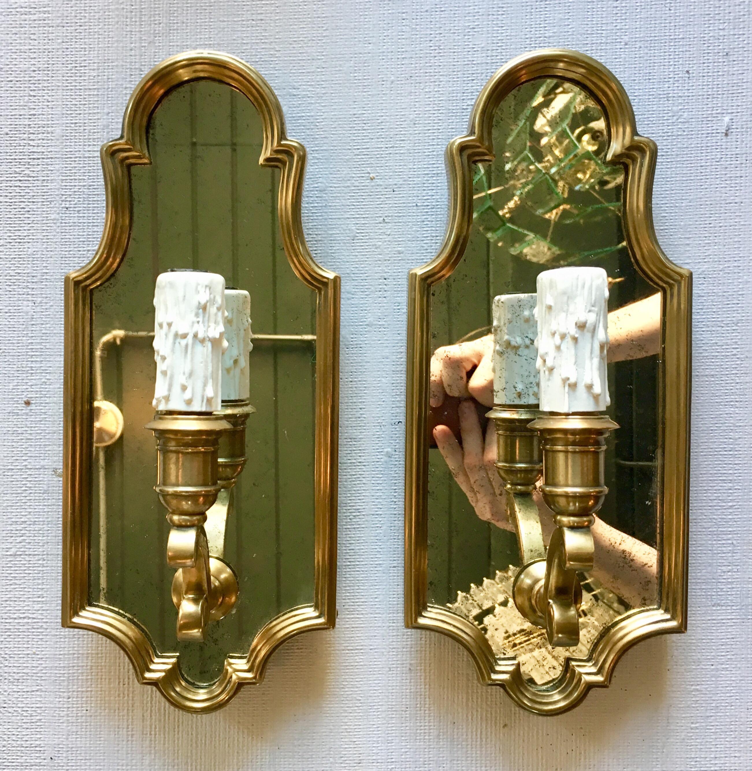 Pair of Hollywood Regency style antique-burnished brass and mirror wall candle light sconces by Chapman & Myers for Visual Comfort Lighting. Gold metal frames feature traditional scrolled detailing with inset aged mirrors. Single candle base 60 Watt