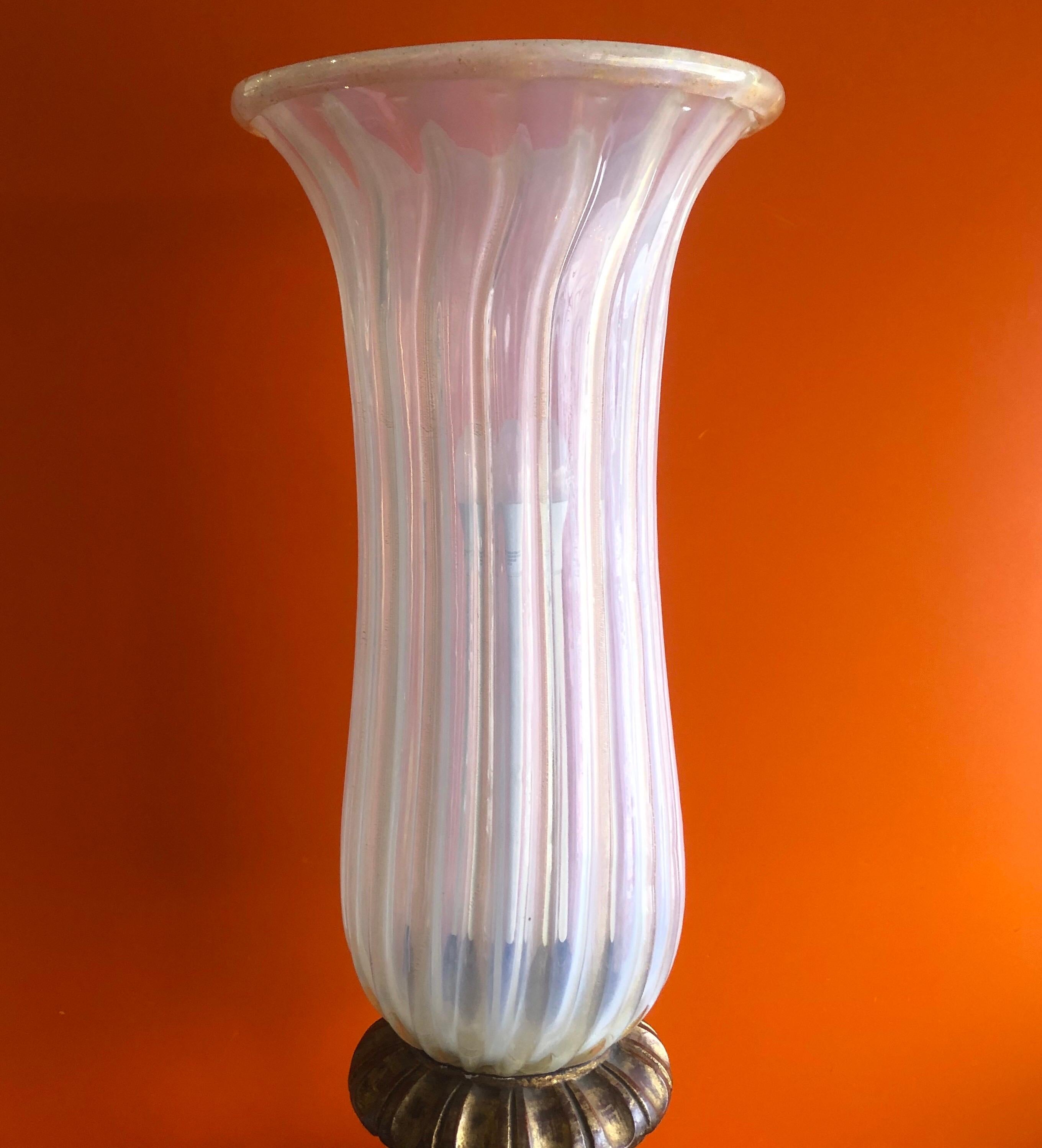 An elegant Hollywood Regency style torchiere lamp by Murano glass, circa 1950s. The glass shade is a cream color with gold flecks throughout and it sits on a gilted hand carved wooden base. Truly and impressive piece!