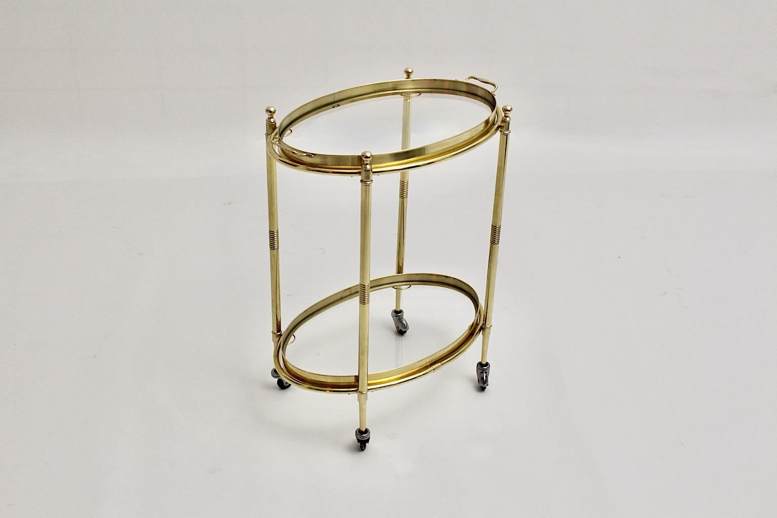 Hollywood Regency Style vintage bar cart or serving trolley or side table from brass and clear glass Italy 1970s.
The elegant and graceful brass bar cart shows 2 removable trays with clear glass and brass frame, while the bar cart has 4 wheels for