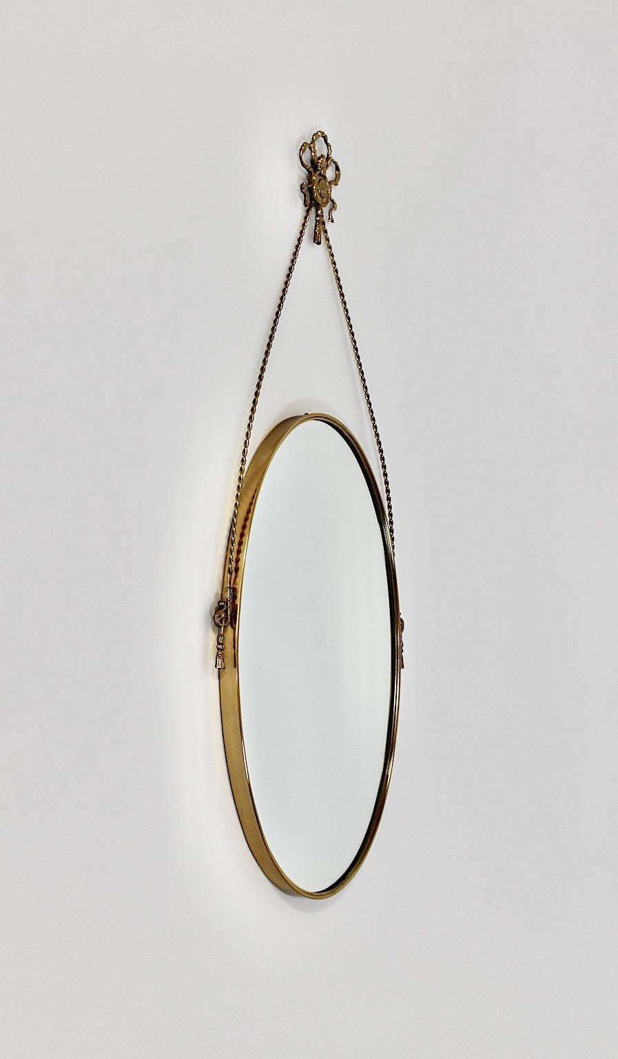 Hollywood Regency style vintage wall mirror from brass 1970s Italy.
A charming wall mirror oval like with beautiful brass details like brass cords, brass bow tie and brass rosette on each side.
This beautiful wall mirror enriches any living space