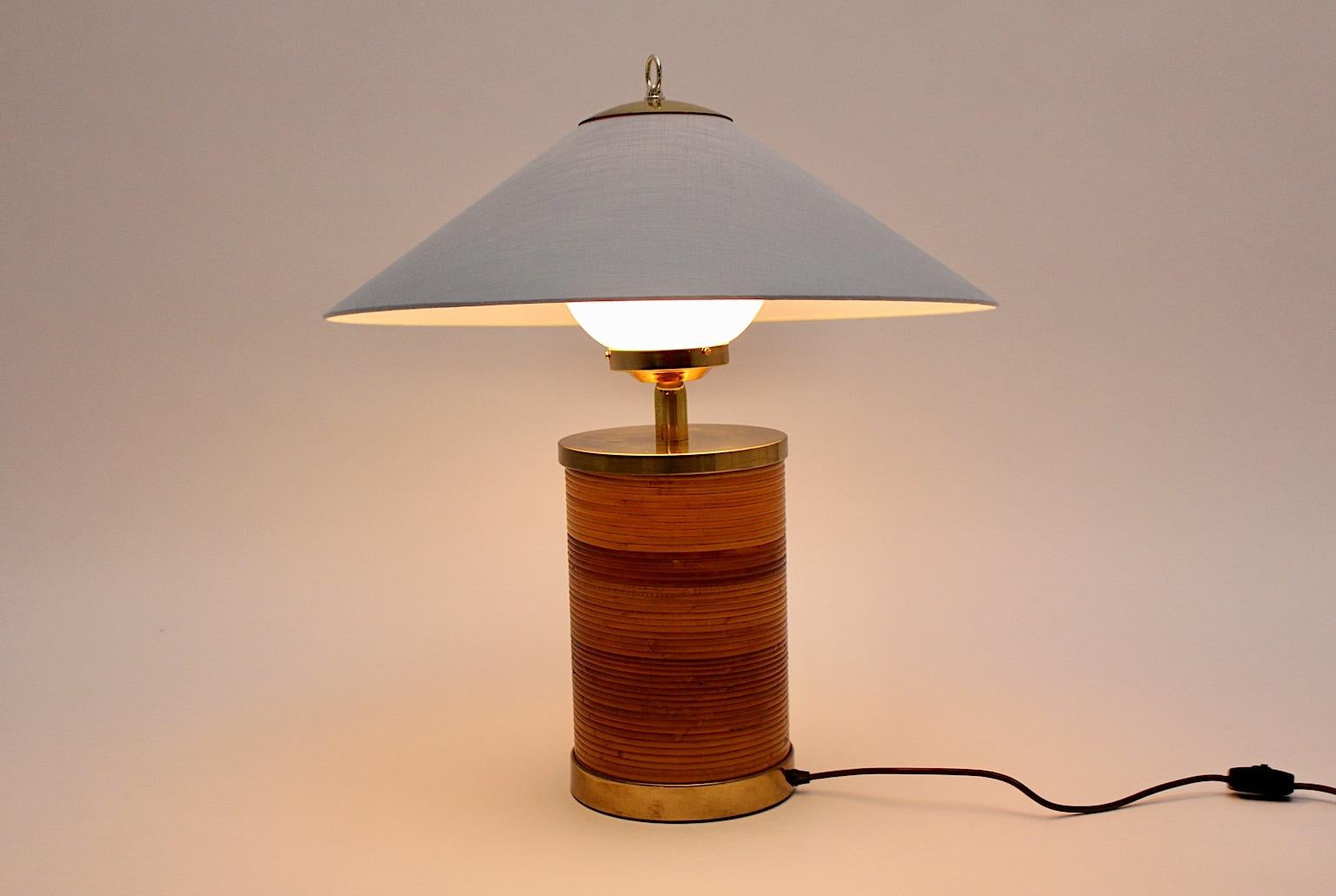 Hollywood Regency style vintage table lamp from rattan and brass with a new made lamp shade from textile fabric in pastel blue color tone, designed in the golden age of Italian design 1970s.
The powerful mix between rattan and brass makes the table