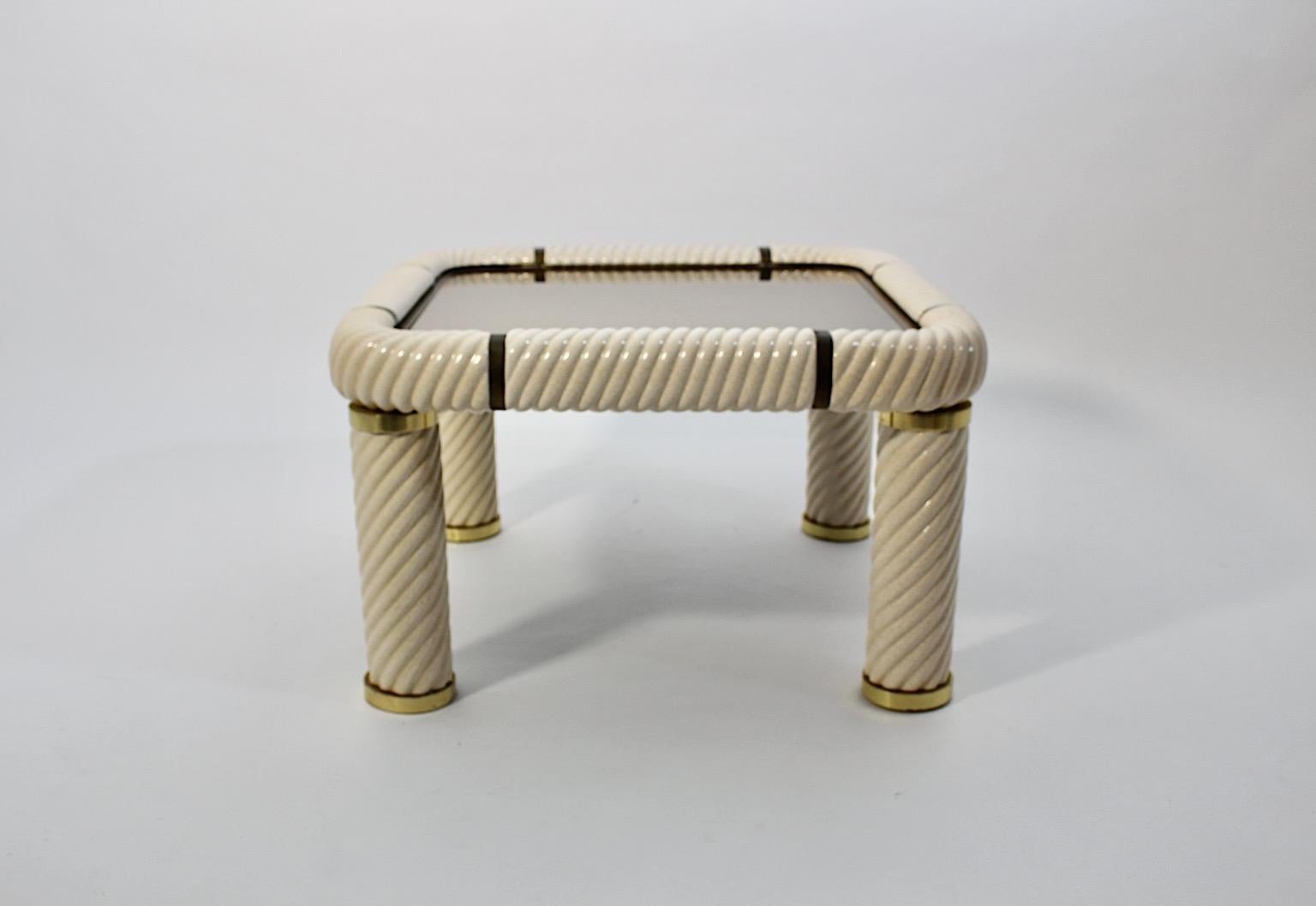 Hollywood Regency Style vintage coffee table by Tommaso Barbi from 
ivory colored ceramic, brass and mirrored metal 1970s Italy.
A stunning new arrival, the coffee table square like by Tommaso Barbi from cream white glazed curled ceramic frame,