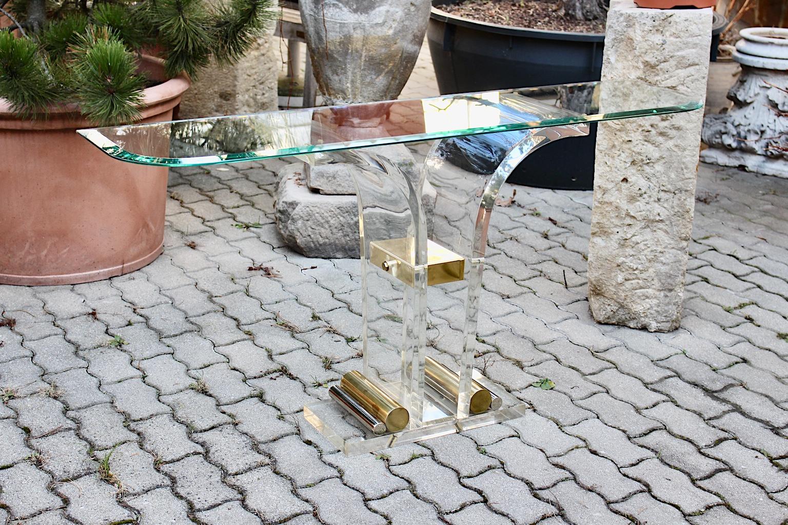 Hollywood Regency style vintage console table or sideboard from lucite, brass and chromed elements and an original facetted glass top, 1970s, Italy.
While the lucite base shows two curved stems with amazing brass and chromed details, the original