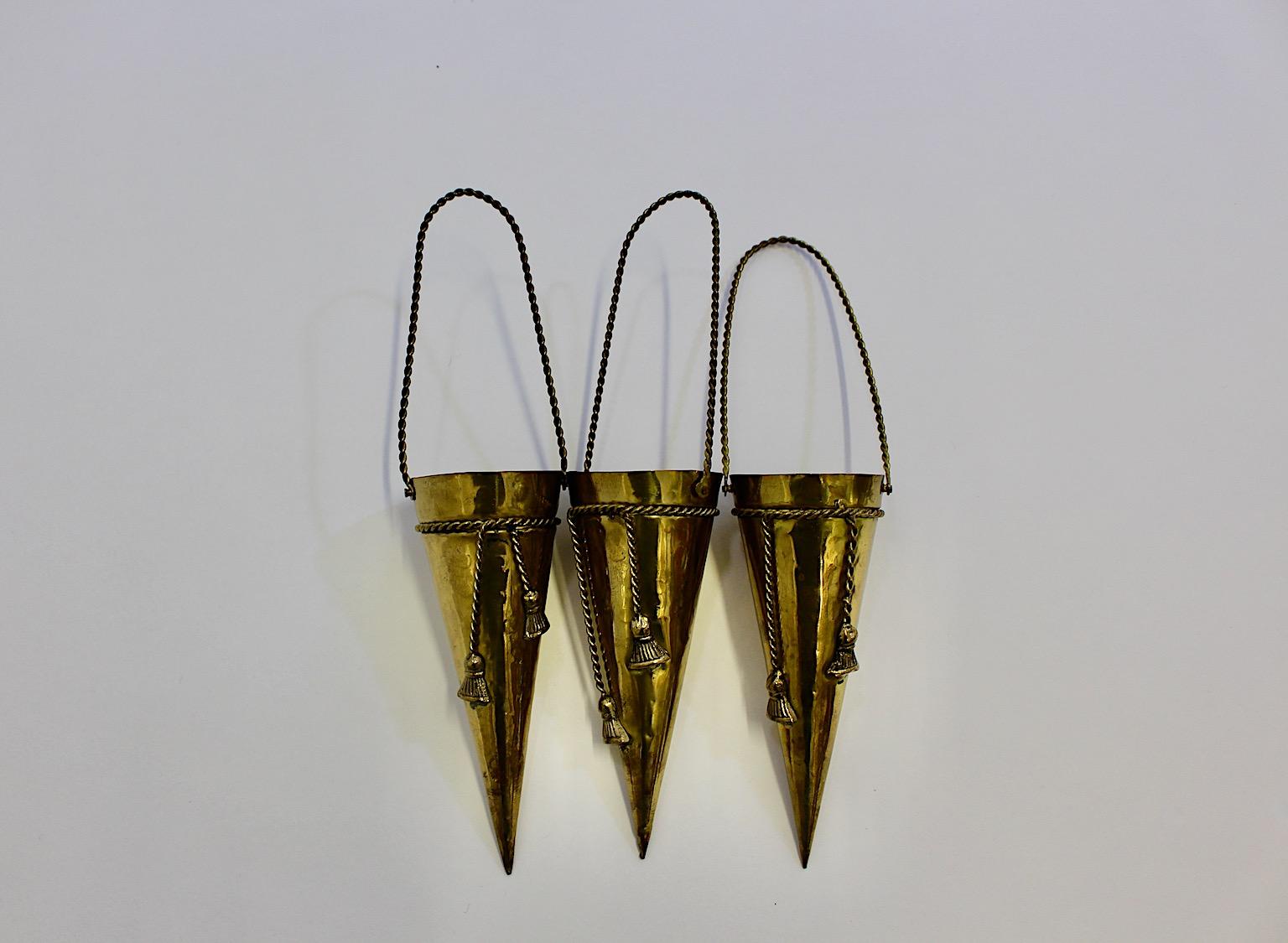 Hollywood Regency Style vintage three ( 3 ) conical wall vessels or vases from brass 1950s France.
A stunning set of three wall vessels cone like with amazing decors like brass cords and tassels amazing to present flowers in unusual way.
Easy to