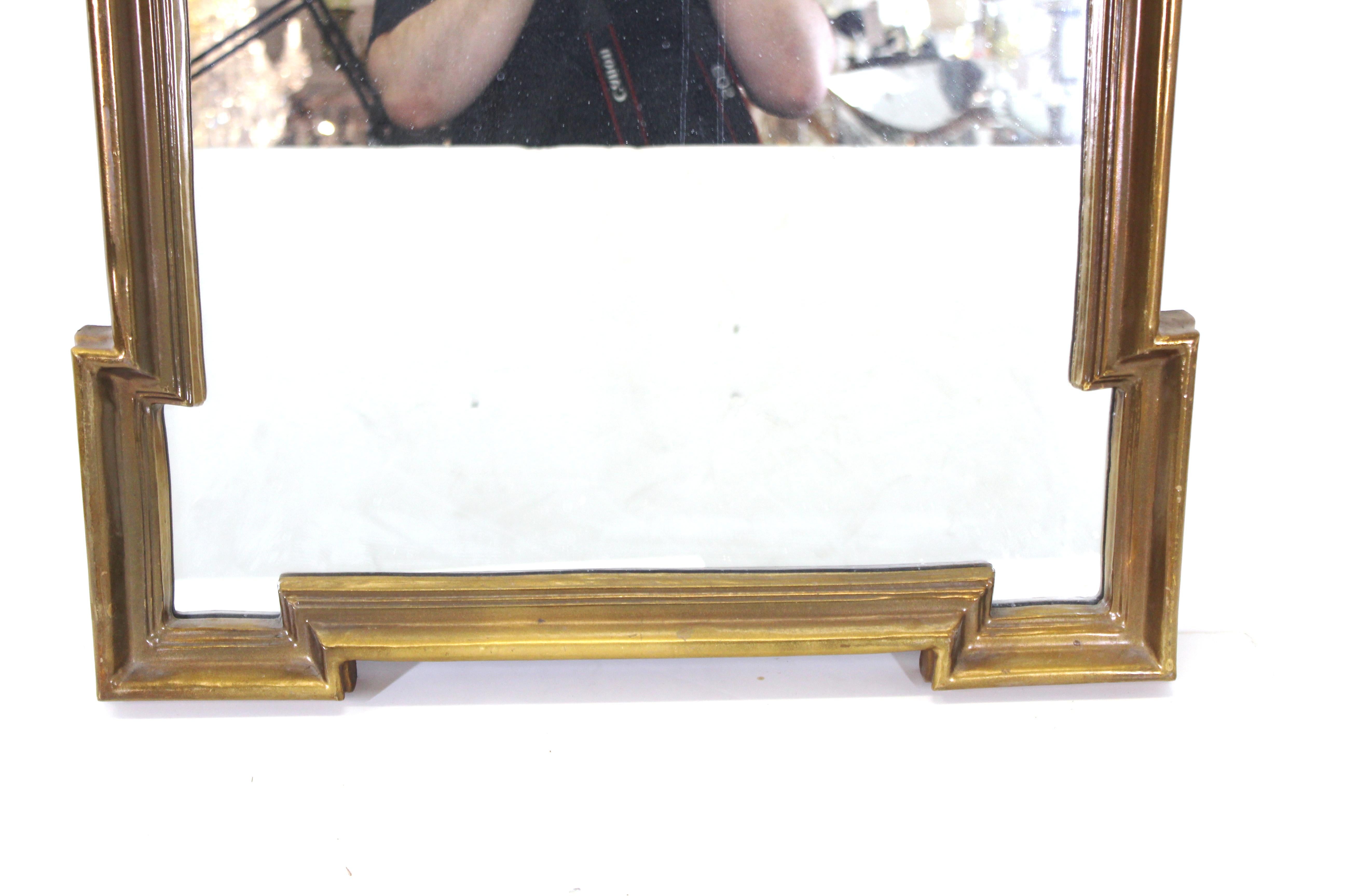 Hollywood Regency style wall mirror with giltwood frame with carved Baroque style elements.