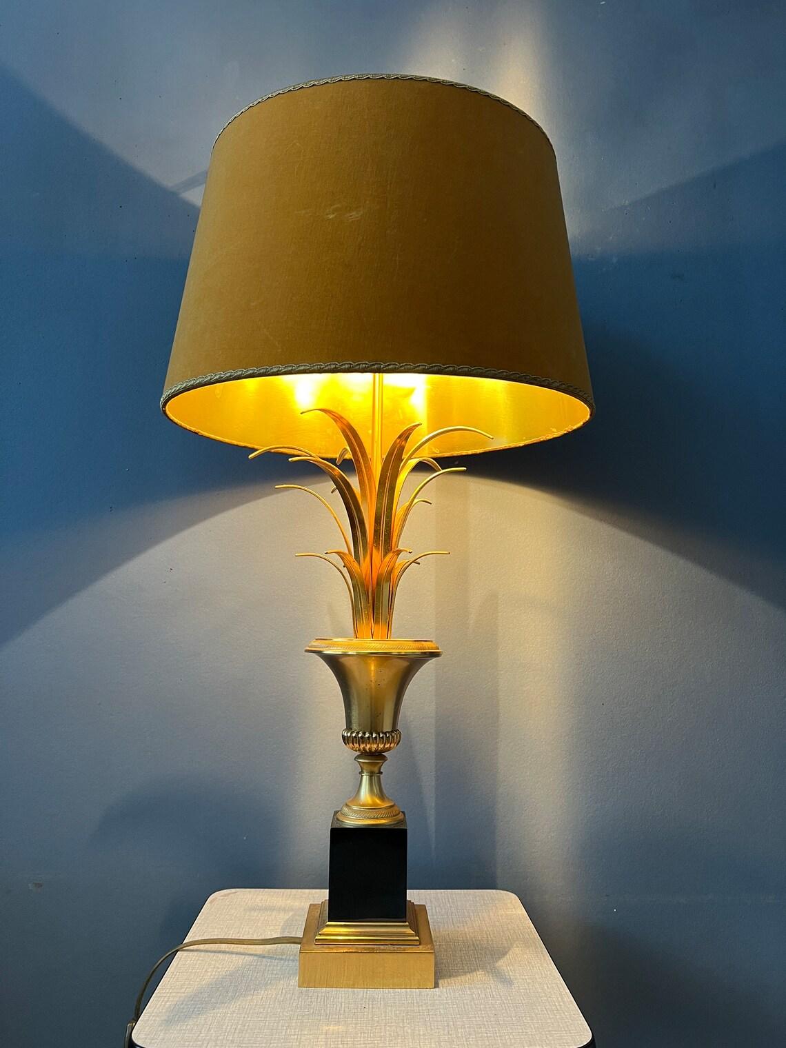 Hollywood regency table lamp with golden base. The lamp requires one E27/26 lightbulb and currently has an EU-plug (usable outside EU with plug-converter).

Additional information:
Materials: Cotton, metal
Period: 1970s
Dimensions:Diameter Shade: 32