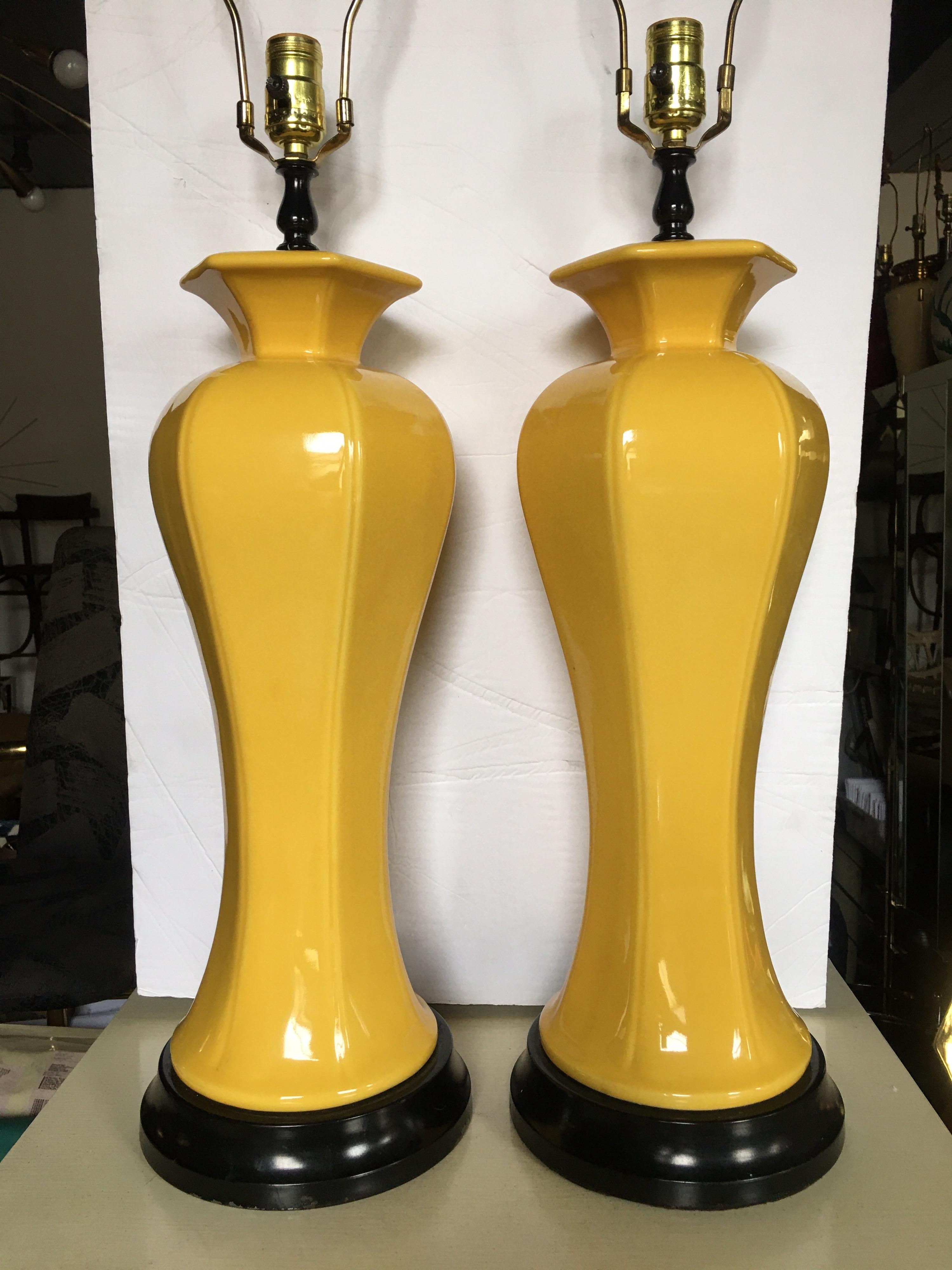 Sculptural Pair of Hollywood Regency Chinoiserie tall sunny yellow ceramic glazed table lamps mounted on black plinth bases. 

Measures: Height to finial 33 inches.
Height to socket 25.5 inches.