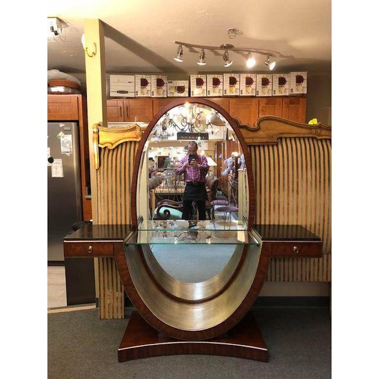 A Hollywood Regency/Art Deco style Hollywood vanity by Thomasville Furniture from the Bogart collection. Beautiful rosewood finish. Vanity features a large oval mirror with a curved base which has a hand applied silver leaf finish. A central glass