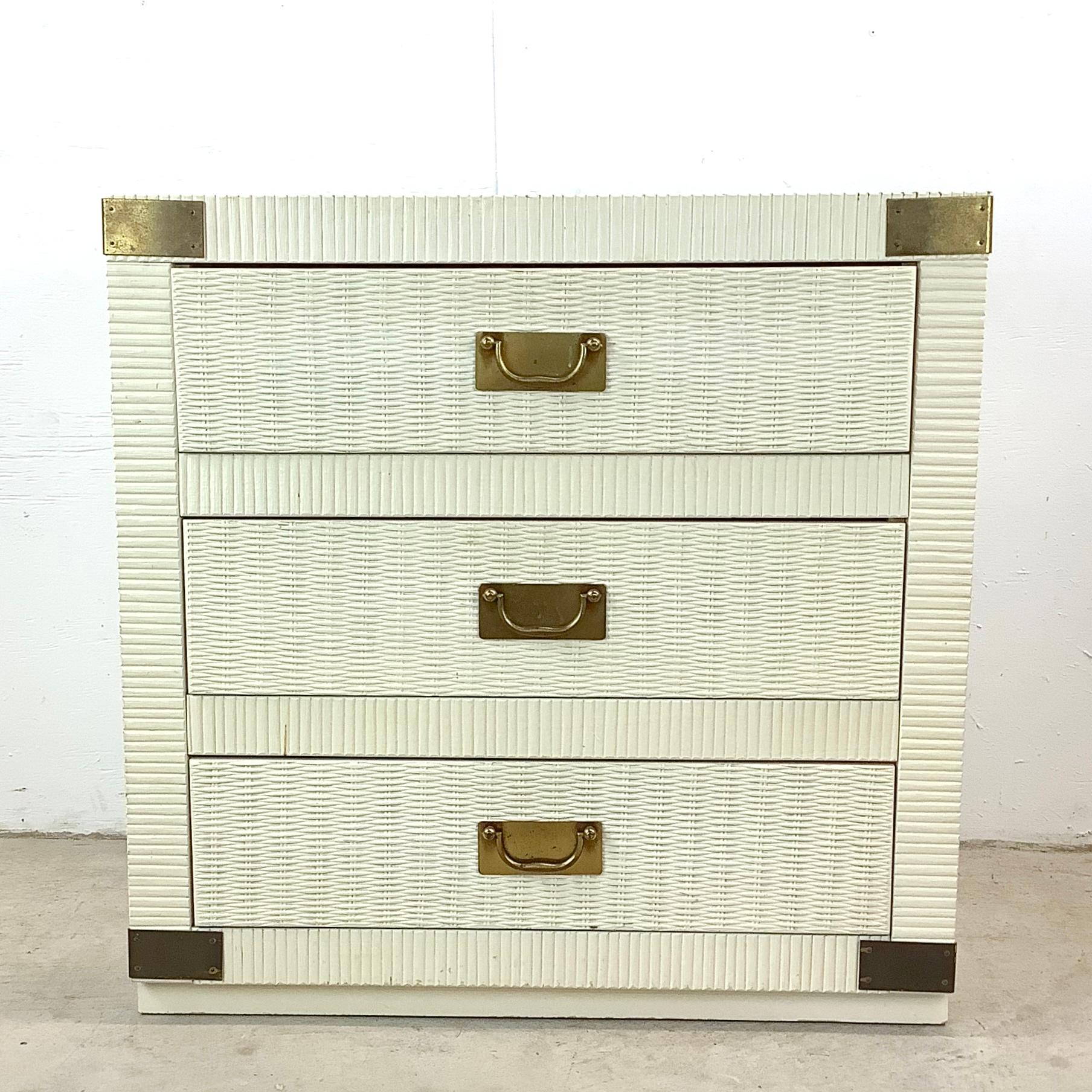 Step into the glamour of the Hollywood Regency era with this Vintage Bachelor's Chest, a piece that exudes both charm and functionality. In its original off-white finish with golden brass campaign hardware, this chest captures the essence of a