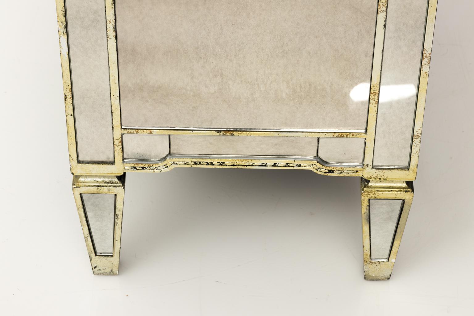 Contemporary Hollywood Regency style three-drawer chest of drawers with antiqued mirrored veneers and antiqued gold trim.
       
