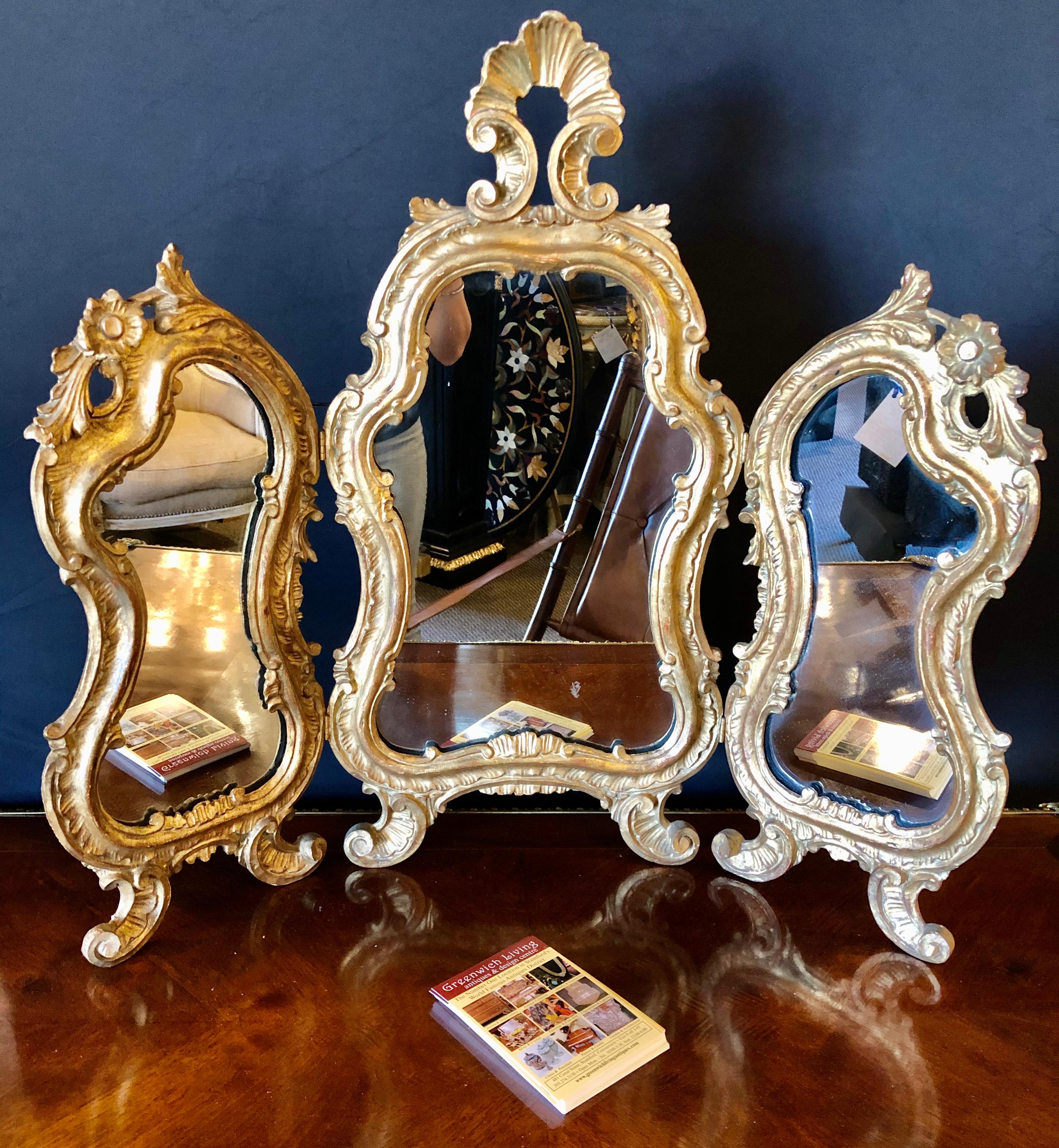 Hollywood Regency three fold table mirror in gold leaf. Sweet tri fold table or vanity mirror in a had leaf gold finish with a carved shell form and rose decorated frame. This mirror can also be hung on the wall flat or three dimensional.


IXXX.