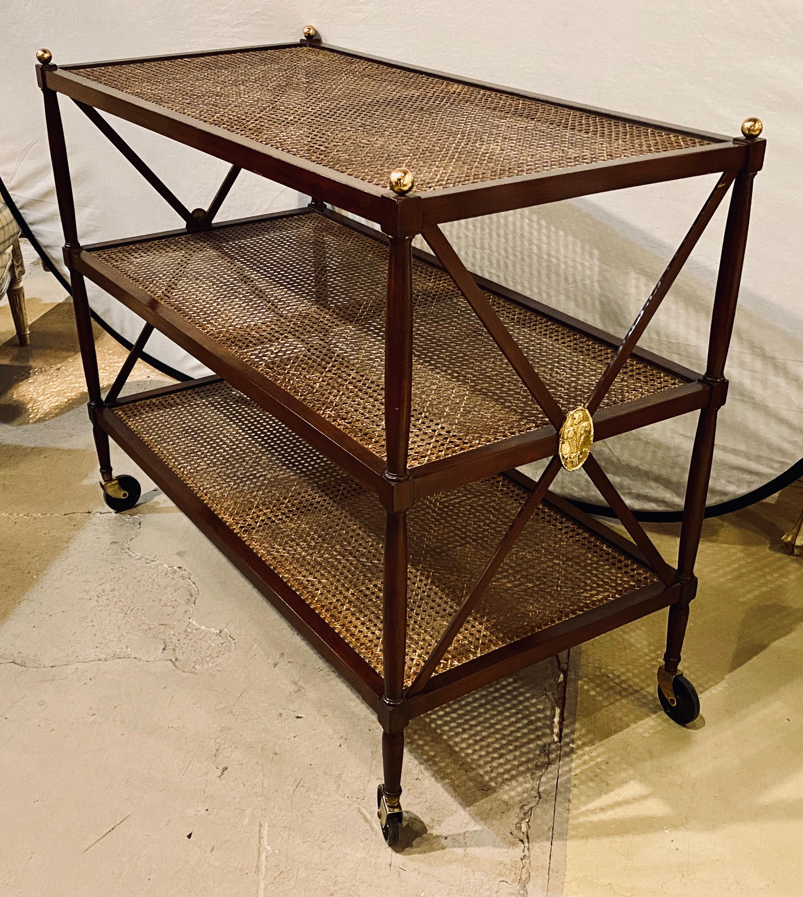 Hollywood Regency three-tier server in the manner of Jansen. This large and impressive serving wagon has full turning smoothly moving casters supporting its mahogany and cane frame with X form design and bronze applicates.
Ehh.