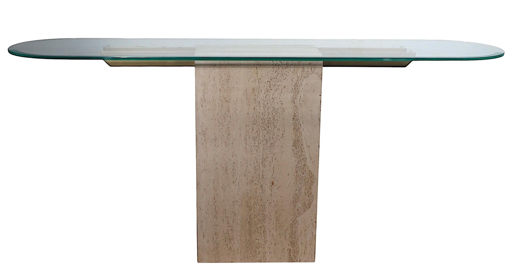 Elegante consola postmoderna estilo Hollywood Regency de Artedi, fabricada en Italia c. 1970/80. La mesa presenta su grueso óvalo original  tapa de cristal biselado, que descansan sobre brazos de metal latonado, montados sobre una base rectangular