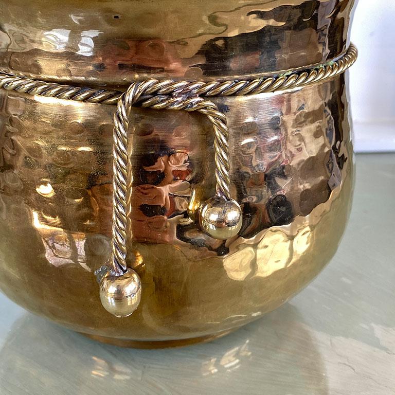 A stunning Hollywood Regency hammered brass planter from India. This round piece features a faux ribbon tied around the top. The bottom includes round felt pads for protection of any surface areas. 

Dimensions:
7